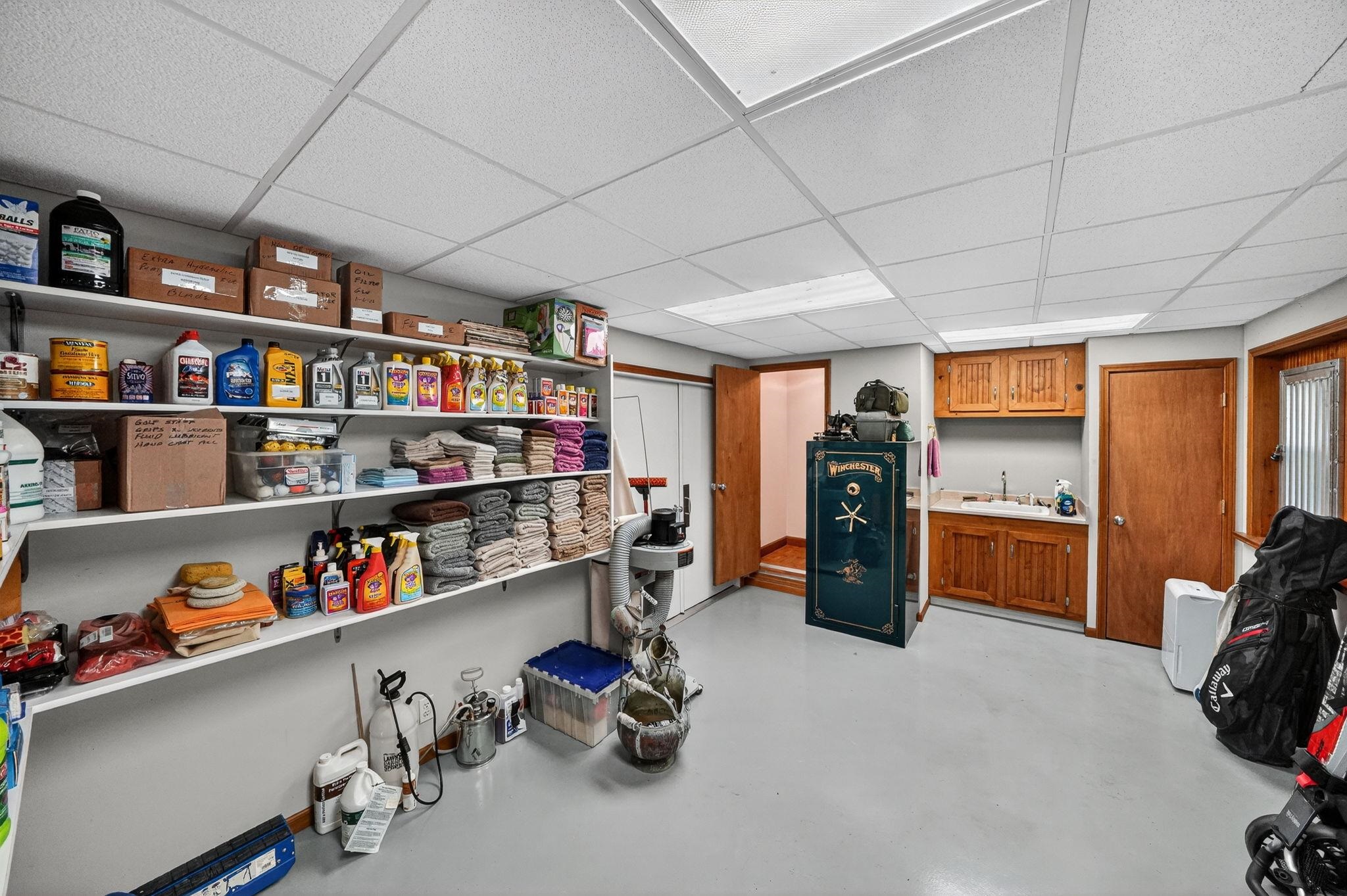 Utility room featuring extensive built-in shelving, an integrated sink with wood cabinetry, and durable flooring