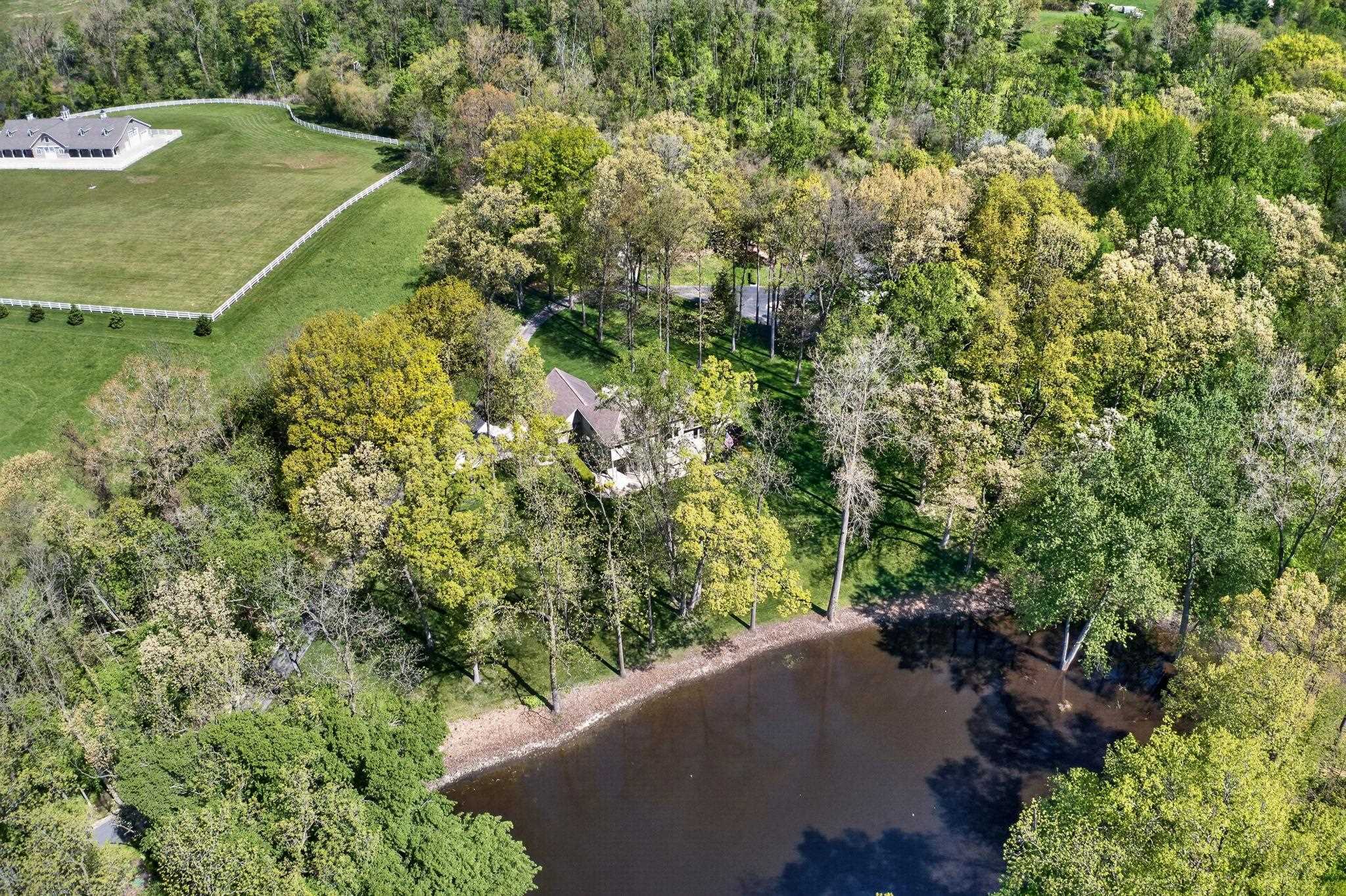 Secluded property nestled among mature trees, featuring a private pond frontage with a natural shoreline