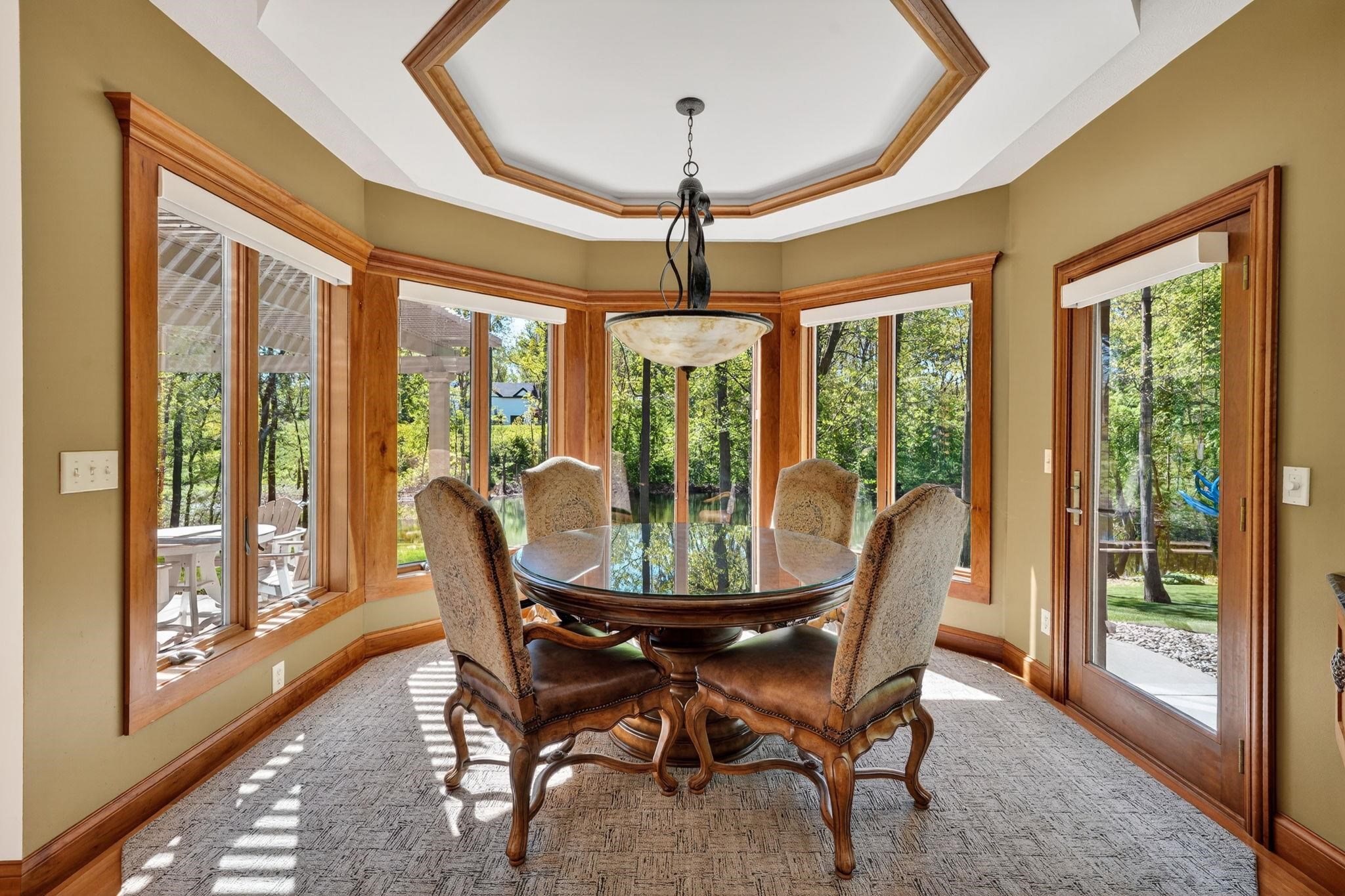Bay window dining area featuring extensive natural light, hardwood trim, a decorative ceiling with a central fixture, and patterned carpeting