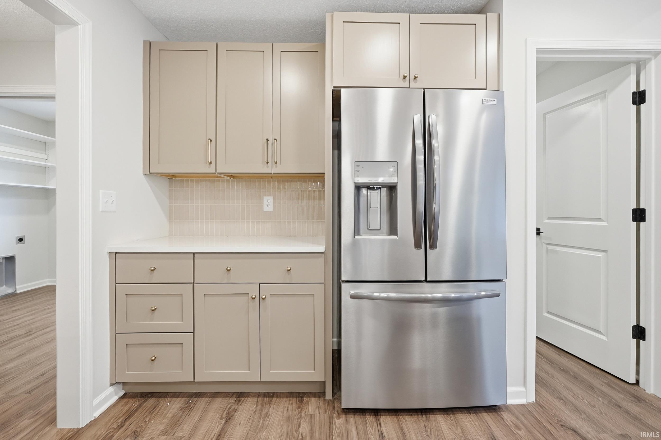 Kitchenette featuring a stainless steel French door refrigerator with an ice and water dispenser, neutral-toned cabinetry, light-toned countertops, and a subway tile backsplash