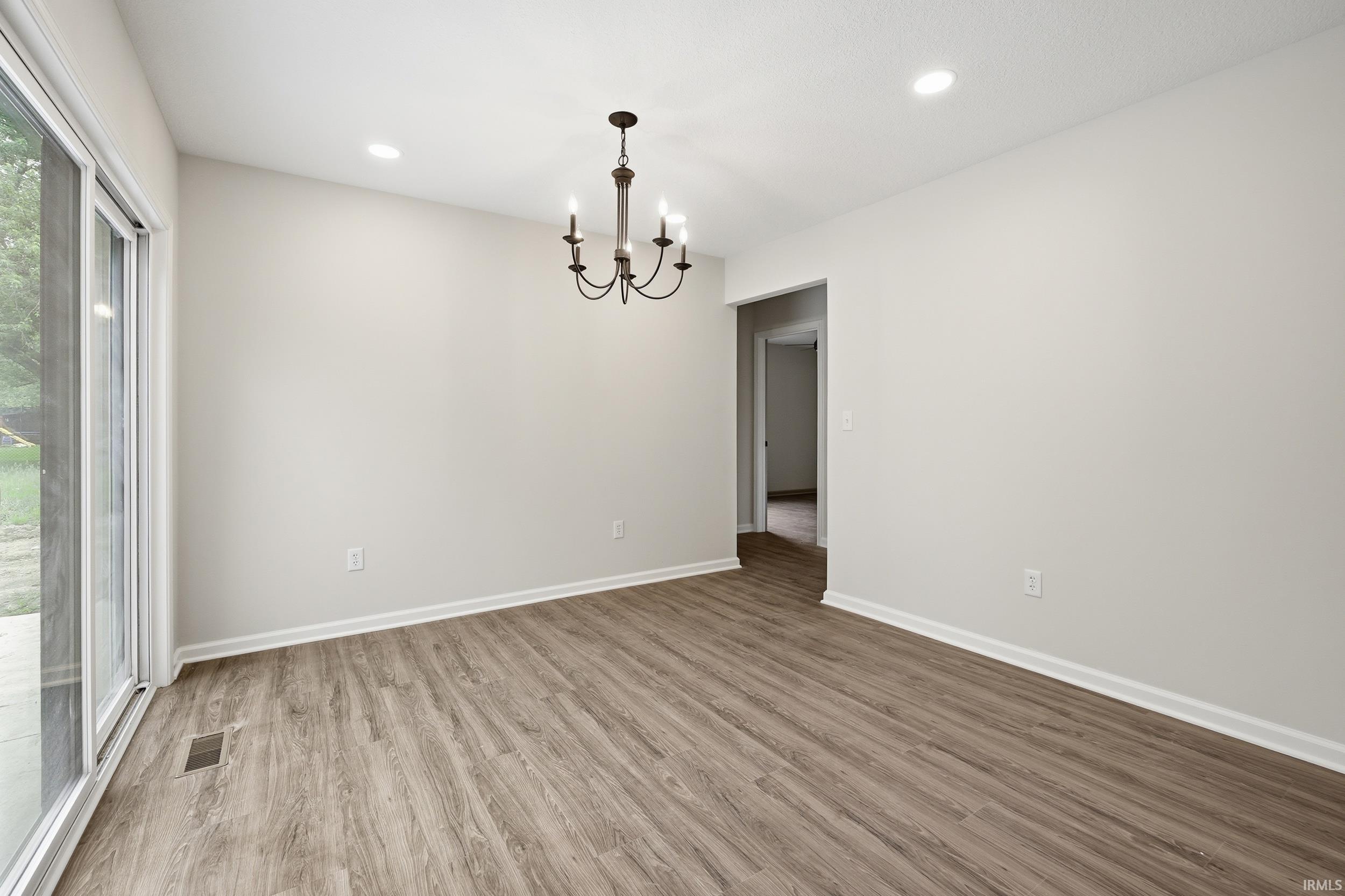 Spacious room featuring wood-finish flooring, white baseboards, and light neutral walls