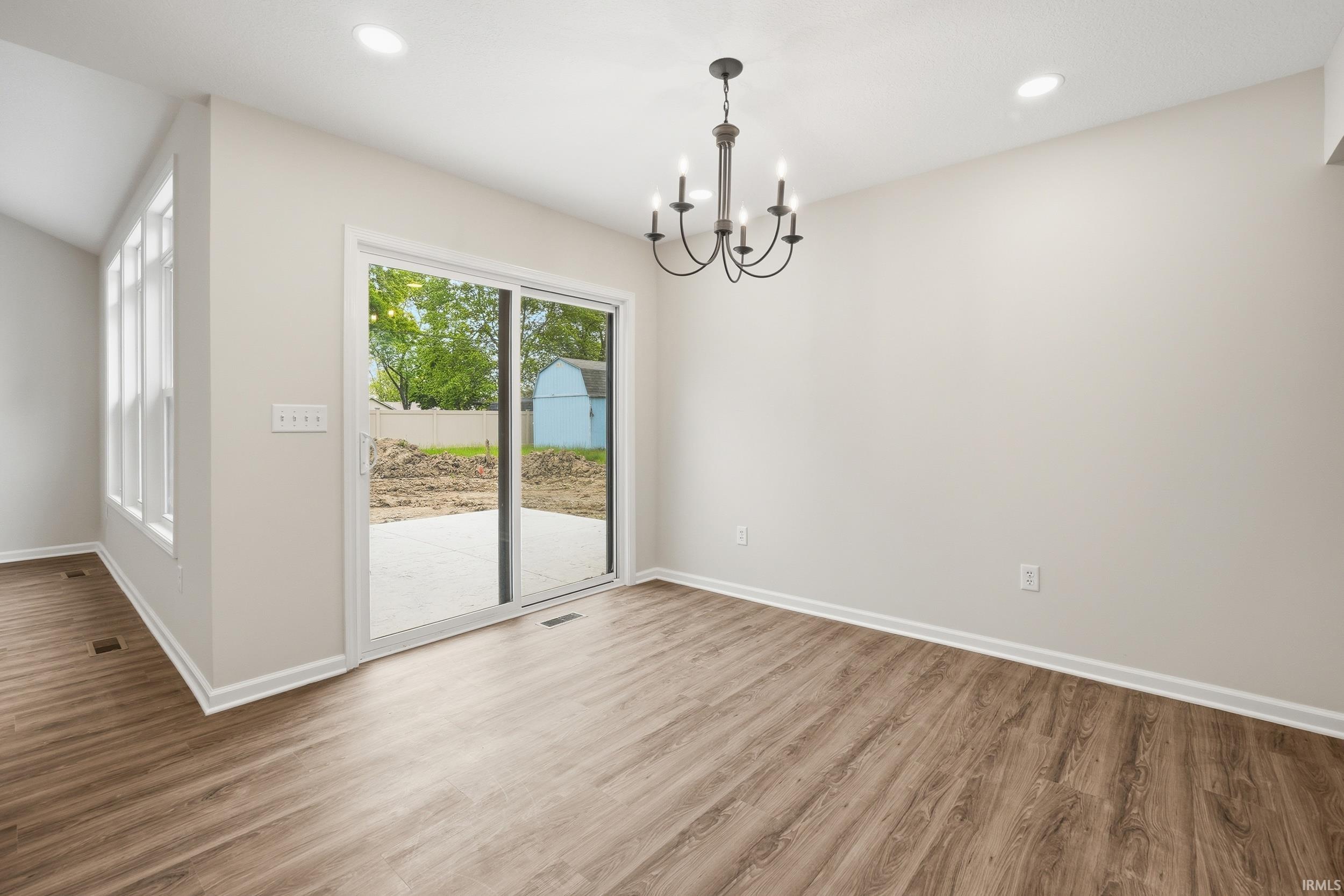 Room featuring wood-finish flooring, recessed lighting, and a contemporary chandelier