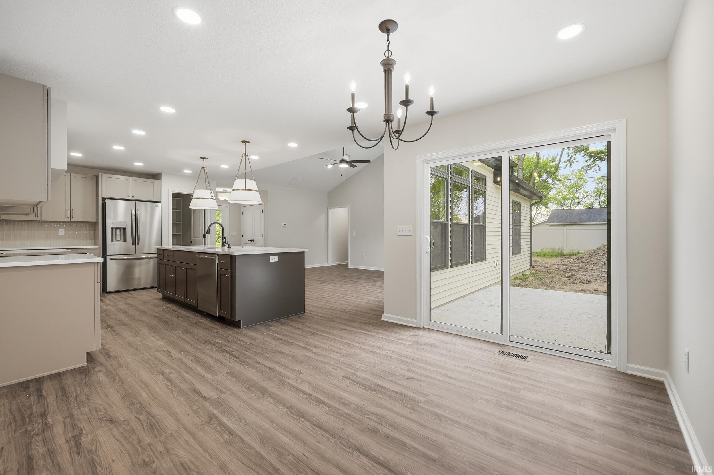 Spacious kitchen featuring an expansive island with built-in cabinetry, stainless steel appliances, and wood-finish flooring