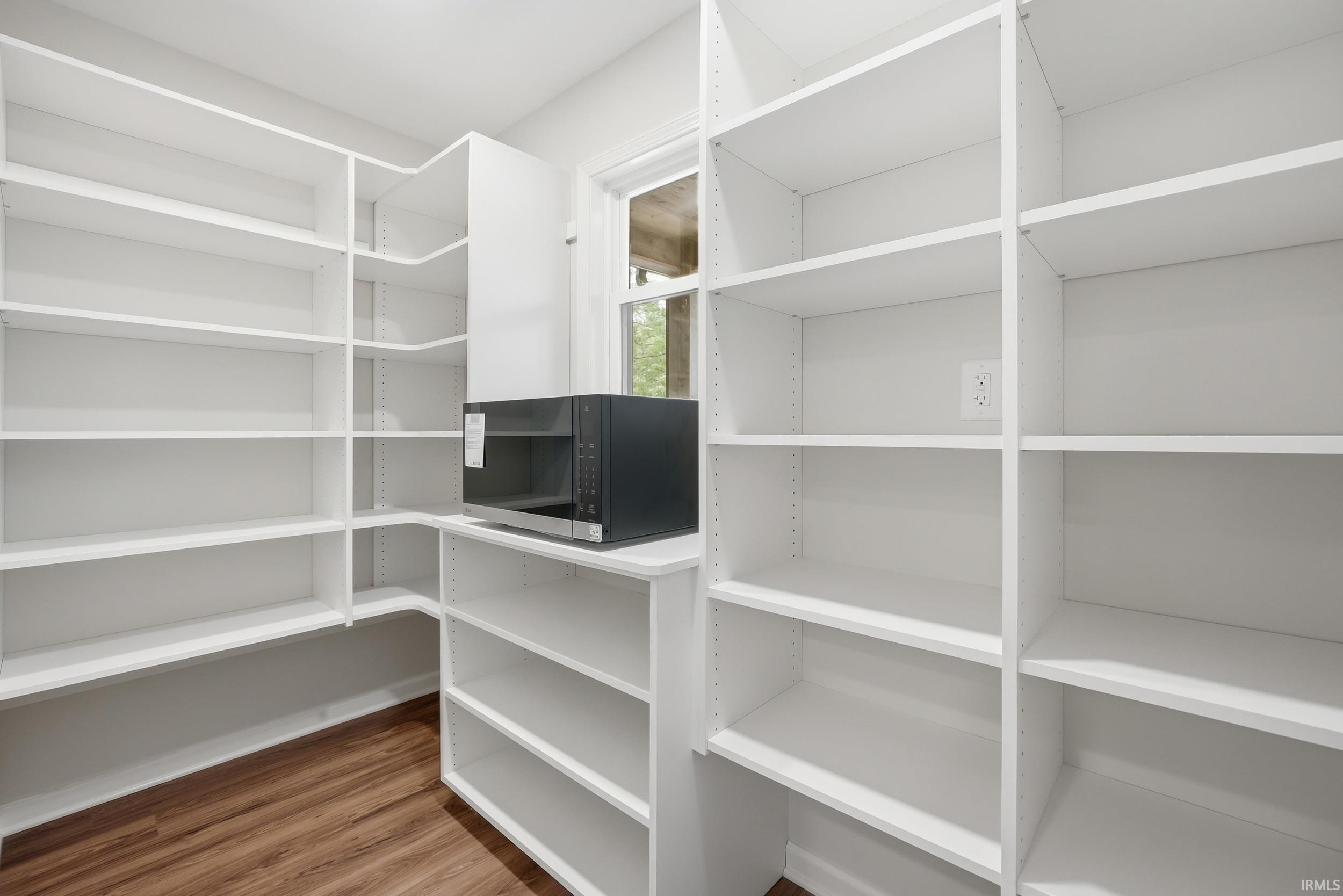 Built-in white shelving system featuring extensive storage capacity, a dedicated counter space, and wood-finish flooring