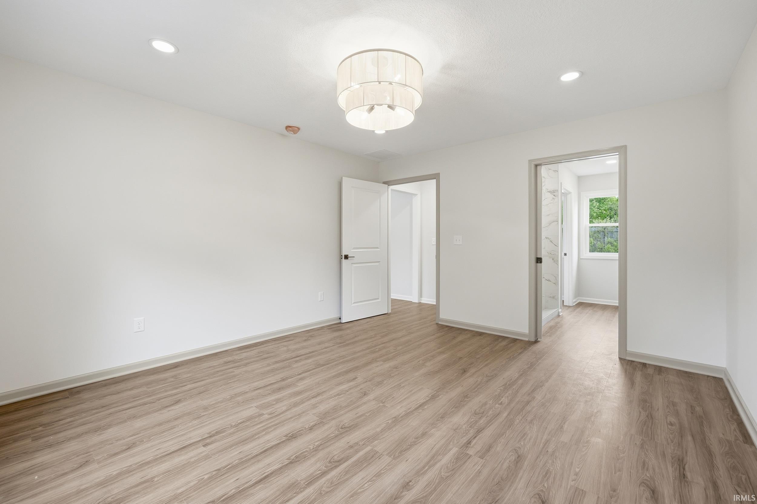 Spacious room featuring wood-finish flooring, recessed lighting, and a contemporary ceiling fixture