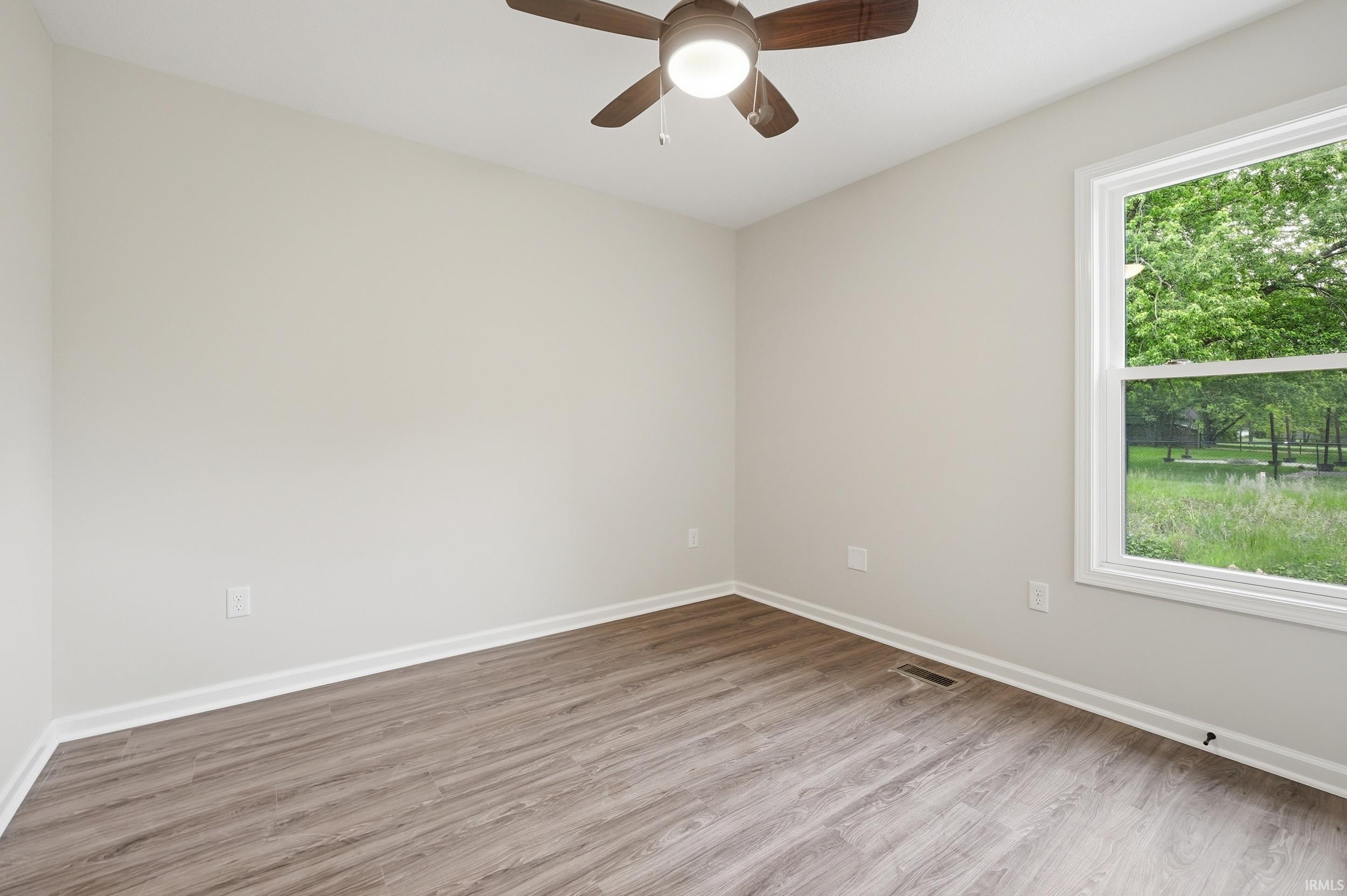 Interior room featuring wood-finish flooring, light-toned wall paint, and white baseboards