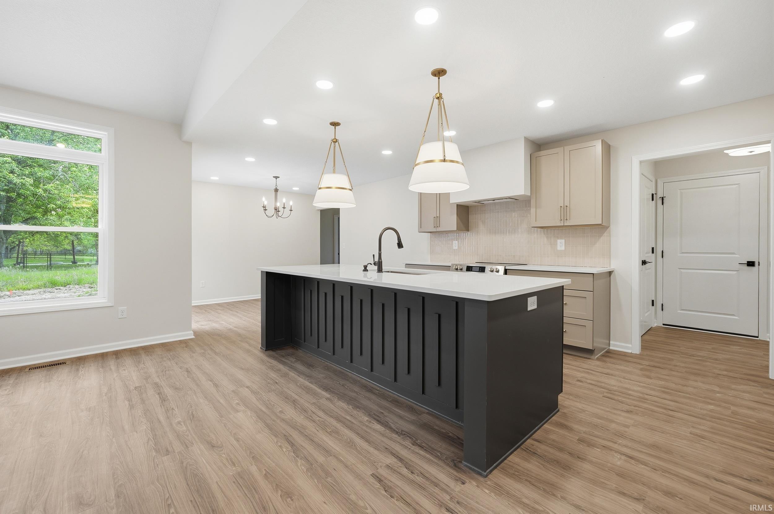 Open-concept kitchen featuring a dark island with a white countertop and double pendant lighting