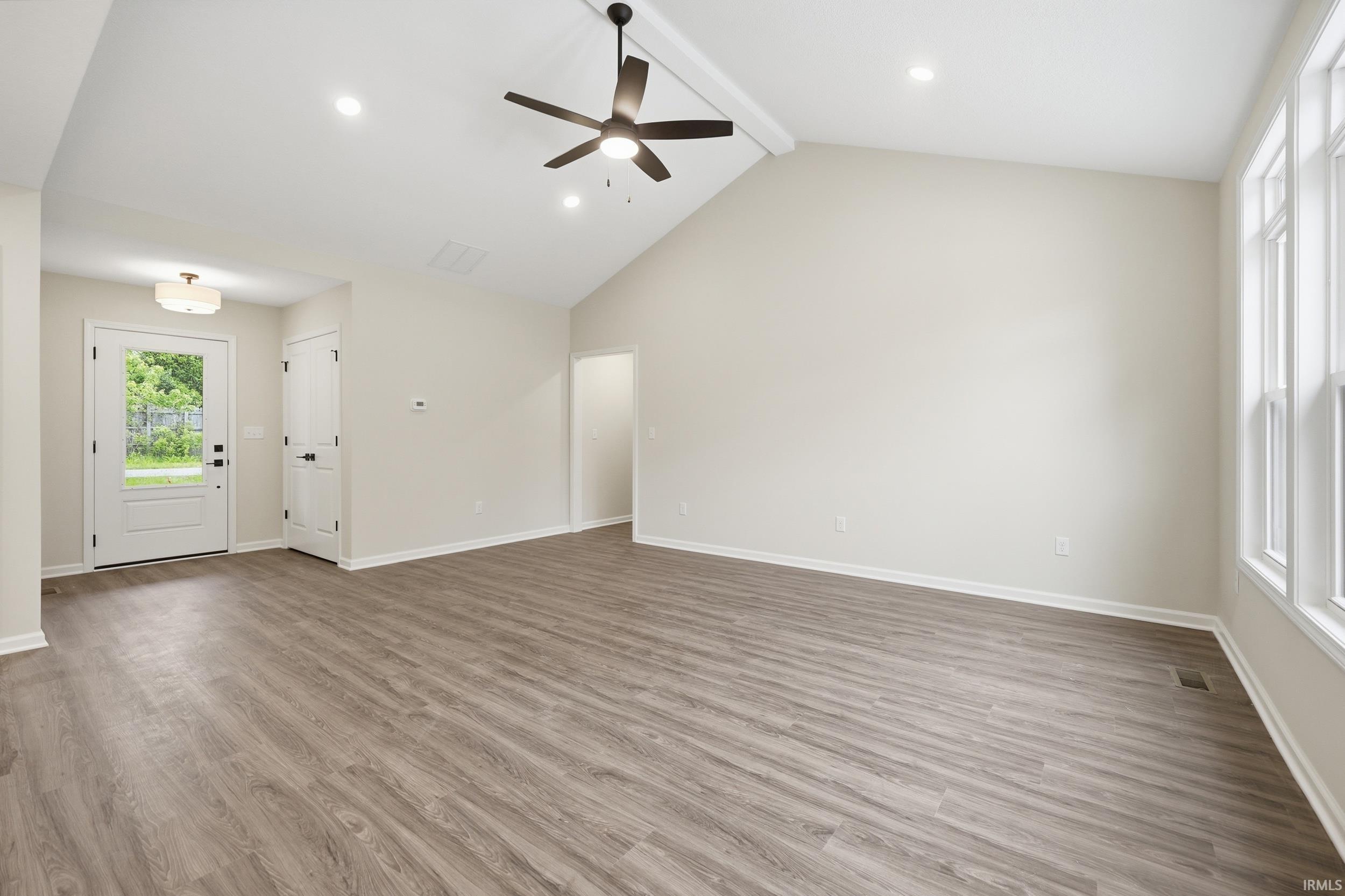 Spacious interior featuring wood-finish flooring, vaulted ceilings, a ceiling fan, and recessed lighting