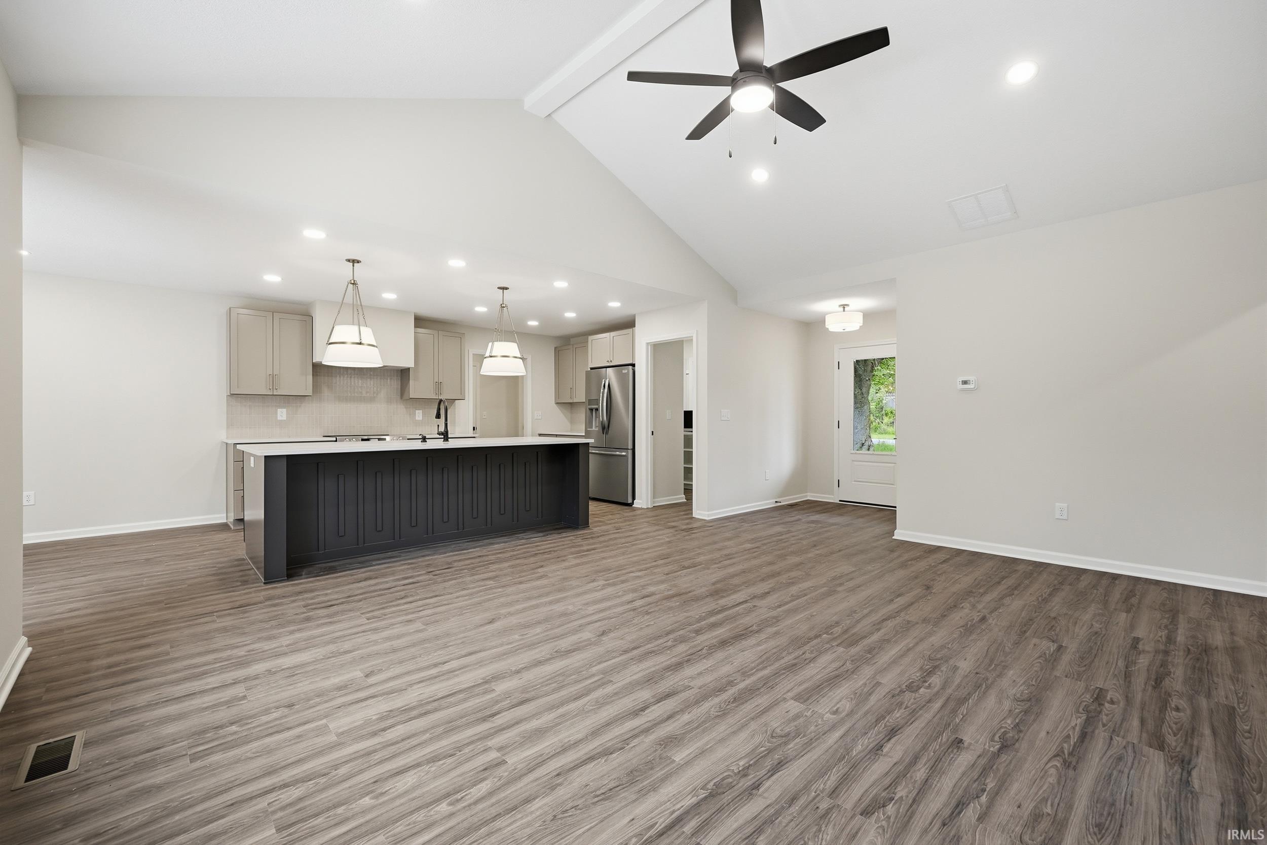 Open-concept living space featuring wood-finish flooring, a vaulted ceiling, and recessed lighting