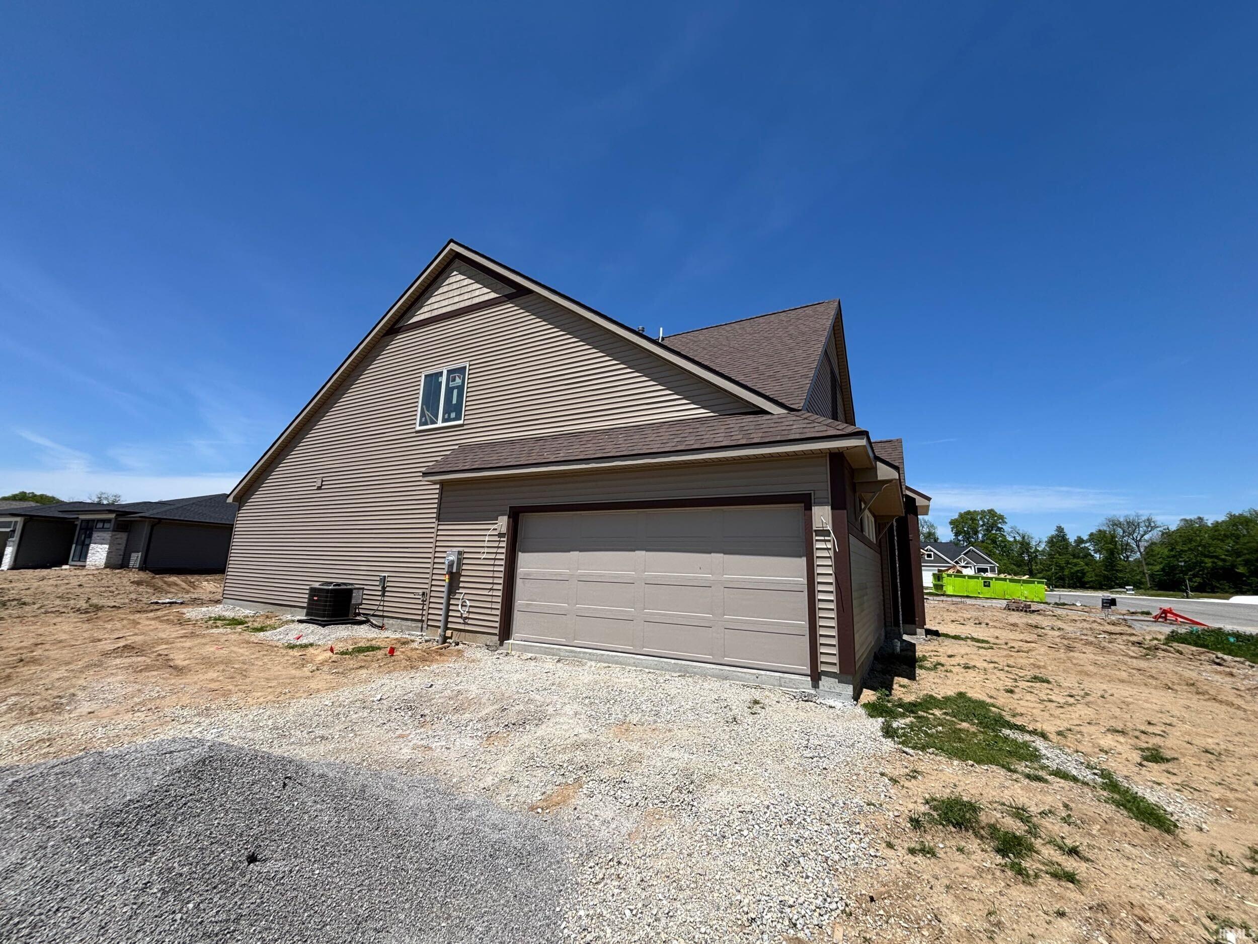 New construction residence featuring tan siding and a brown shingle roof