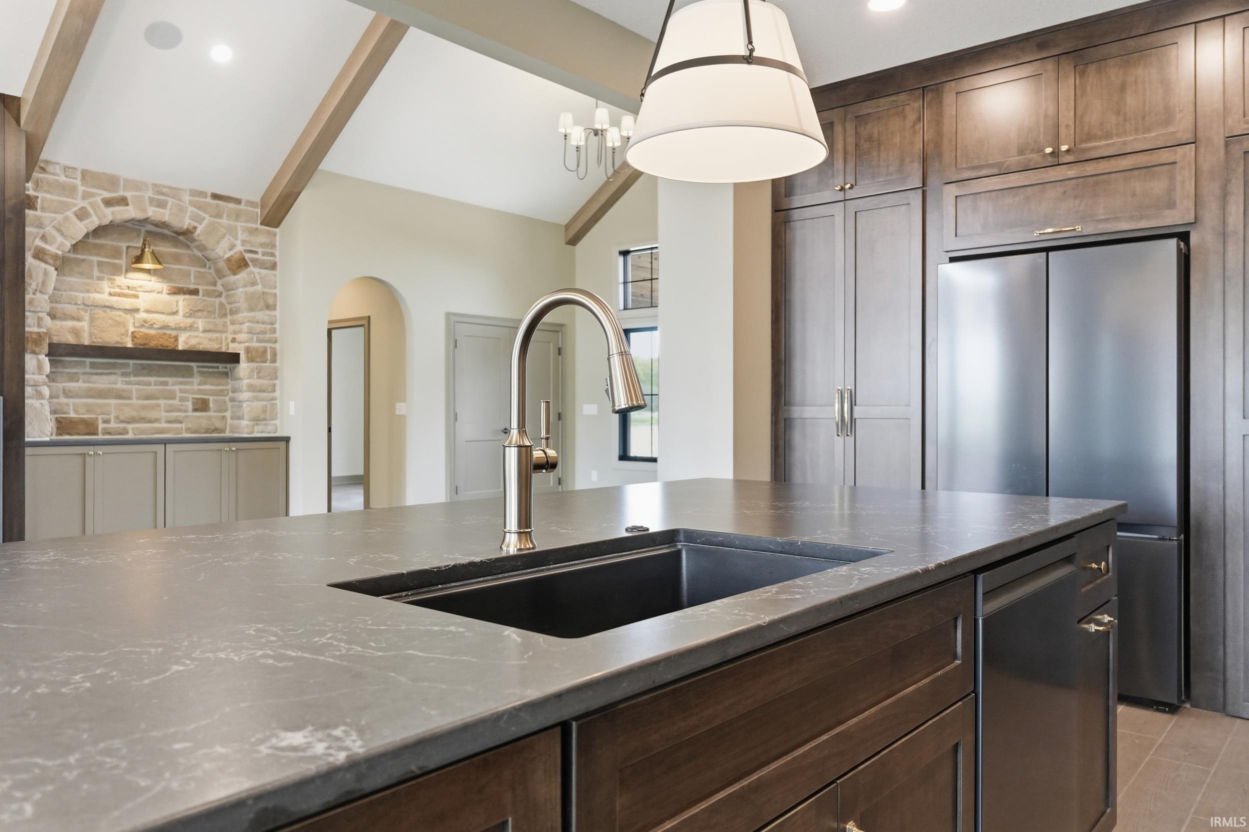 Kitchen island featuring a dark composite sink, brushed nickel faucet, and a stone-look countertop