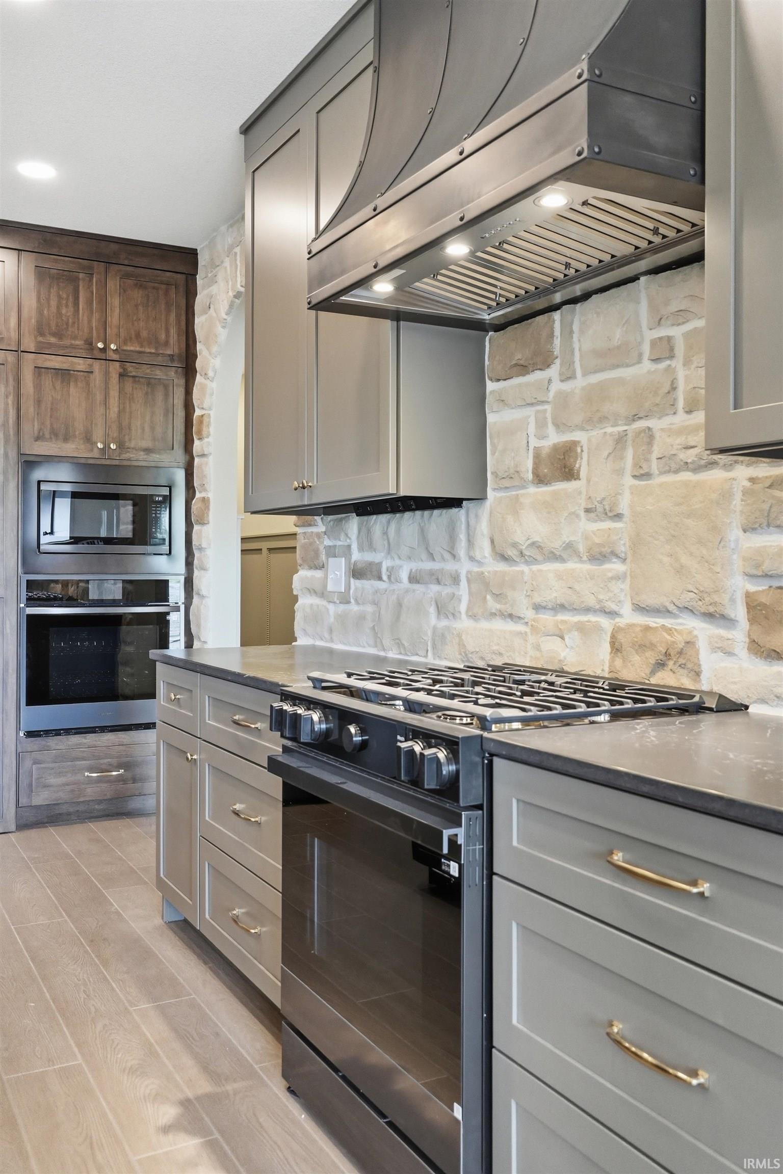 Gourmet kitchen featuring a built-in oven, microwave, and range with a custom metal hood