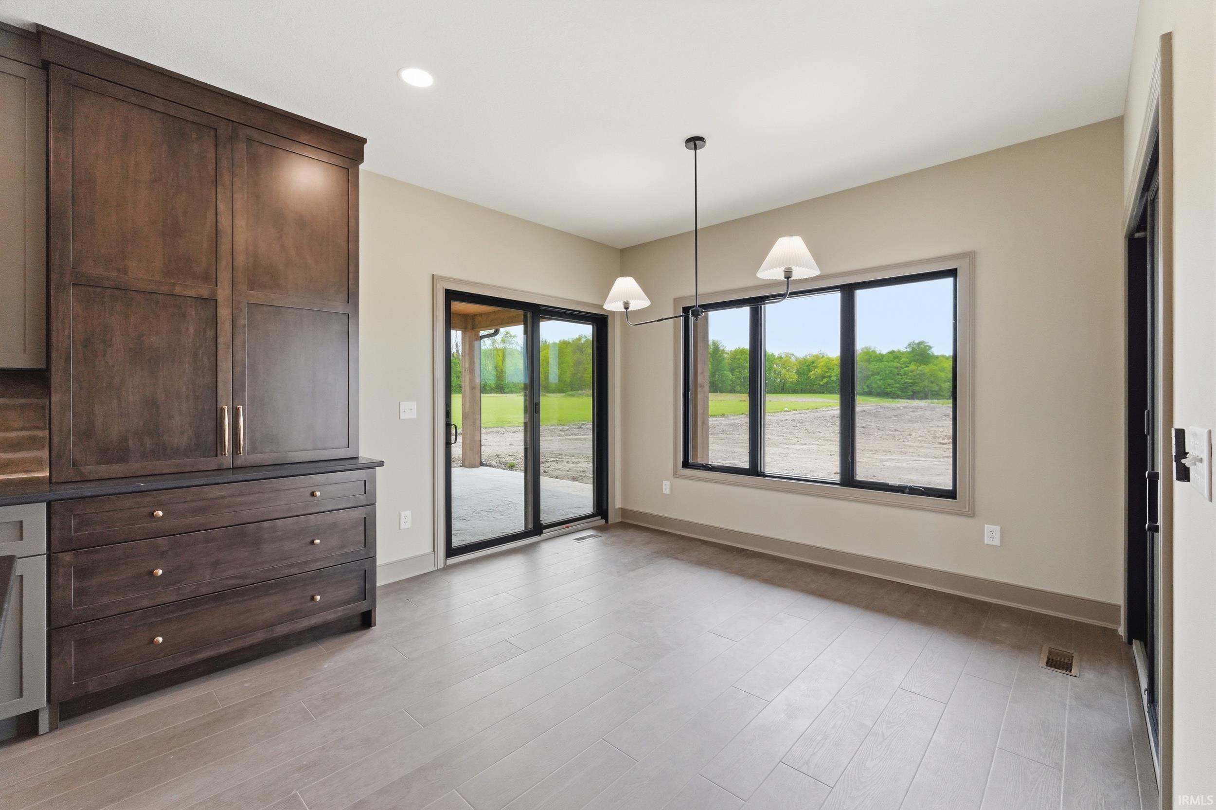 Dining area featuring wood-finish flooring, two pendant light fixtures, and a large window with black framing