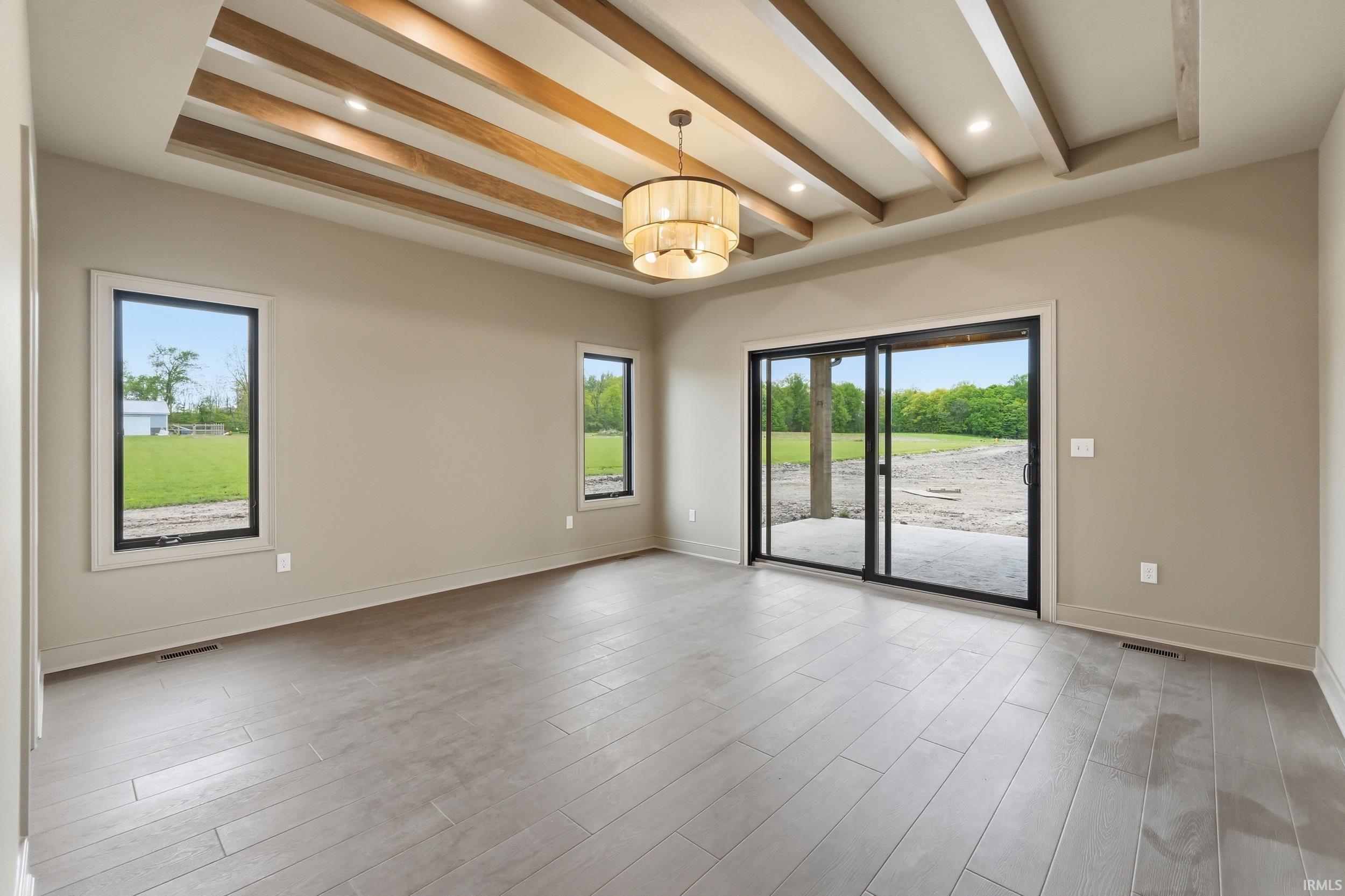 Spacious interior featuring a coffered ceiling with exposed wood beams, a central chandelier, and recessed lighting