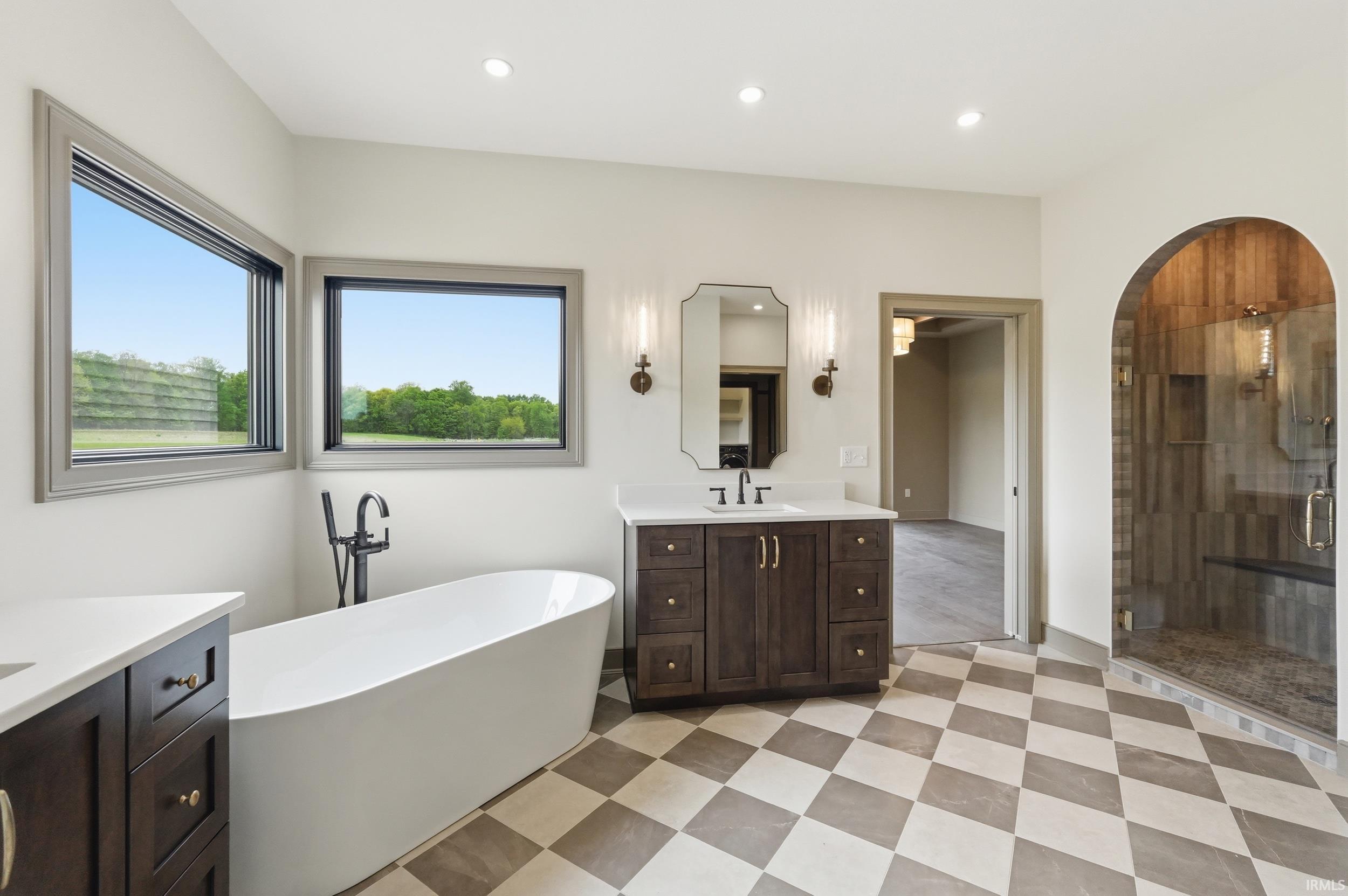 Spacious bathroom featuring a freestanding soaking tub, dual vanities with white countertops, and checkerboard floor tiling