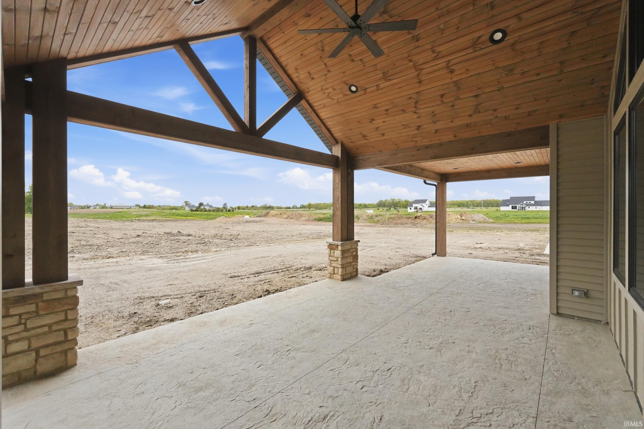 Expansive covered patio featuring a wood plank ceiling and exposed wood beams