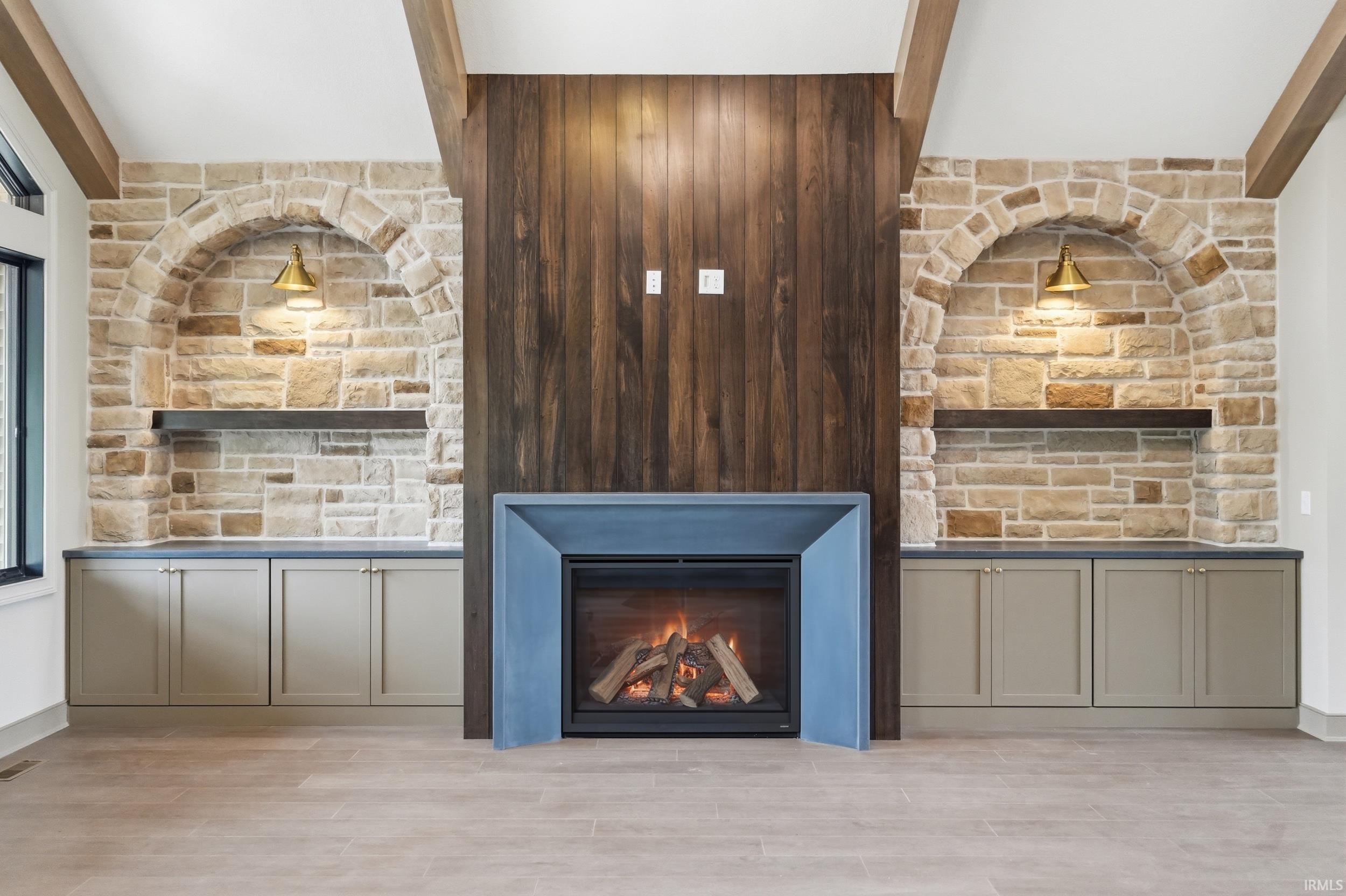 Stone veneer fireplace wall with a wood panel accent, flanked by built-in cabinetry with dark countertops