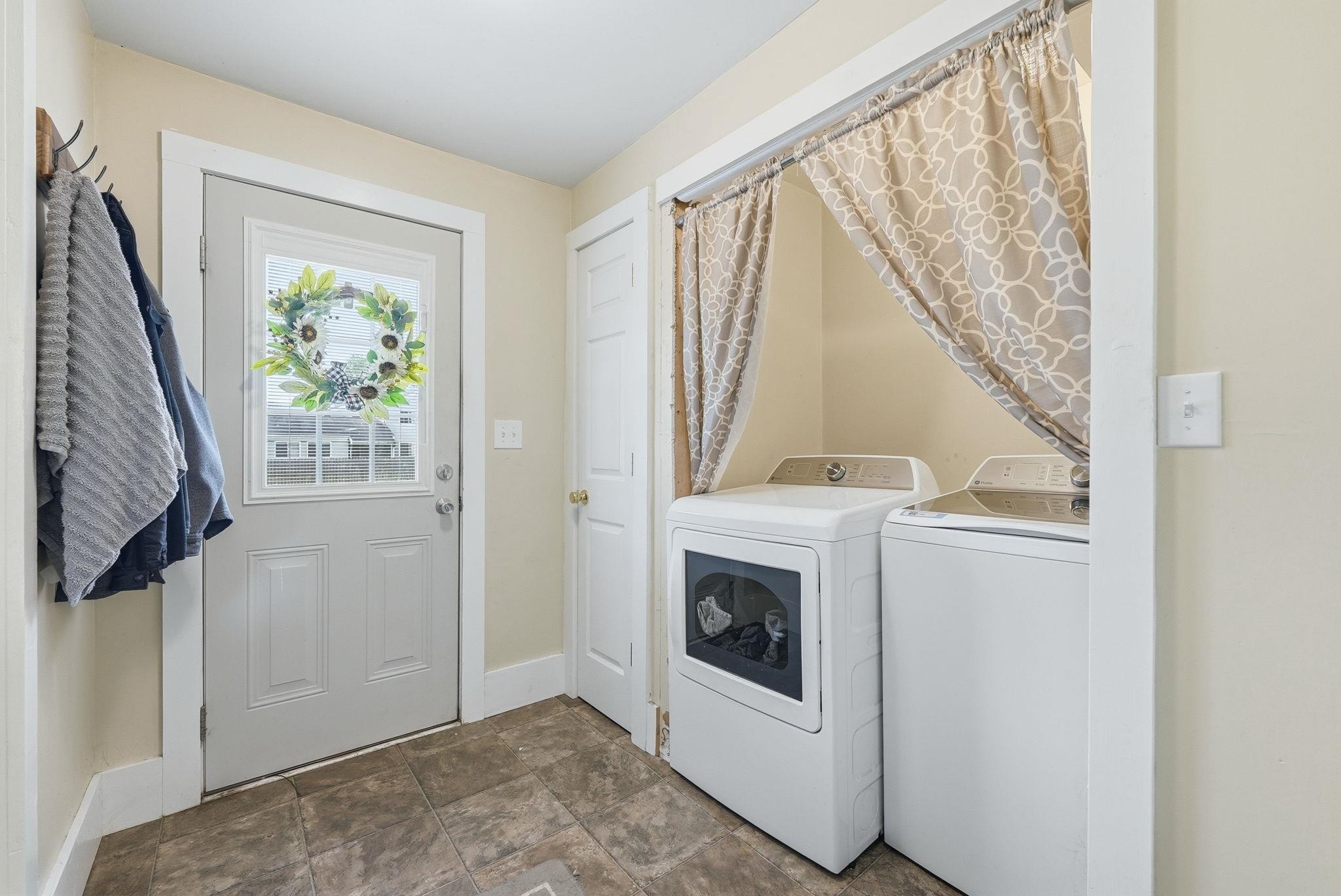 Laundry area featuring a side-by-side washer and dryer, privacy curtain, and durable tile-look flooring