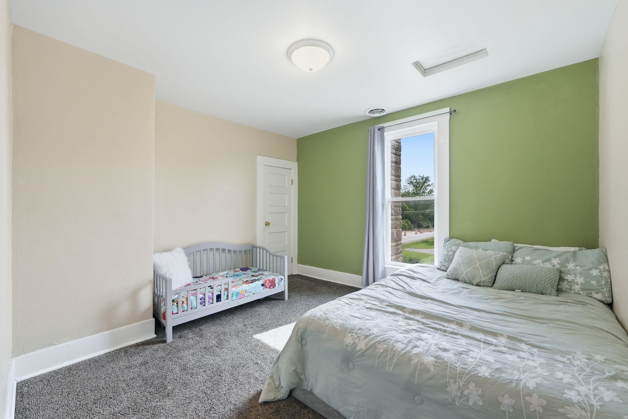 Carpeted room with a ceiling light fixture and a window with white trim
