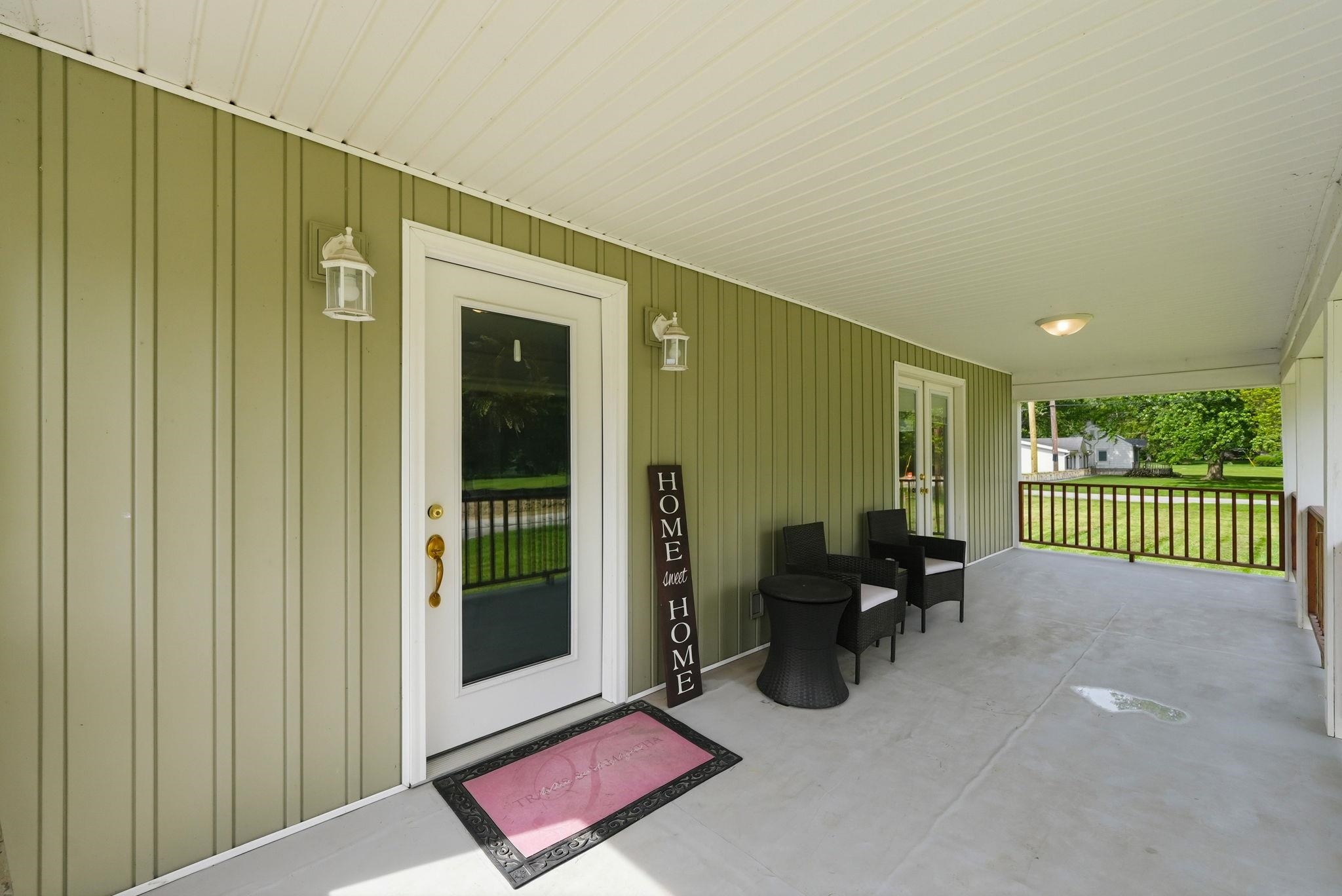 Expansive covered porch featuring a concrete surface, white beadboard ceiling, and light green vertical siding