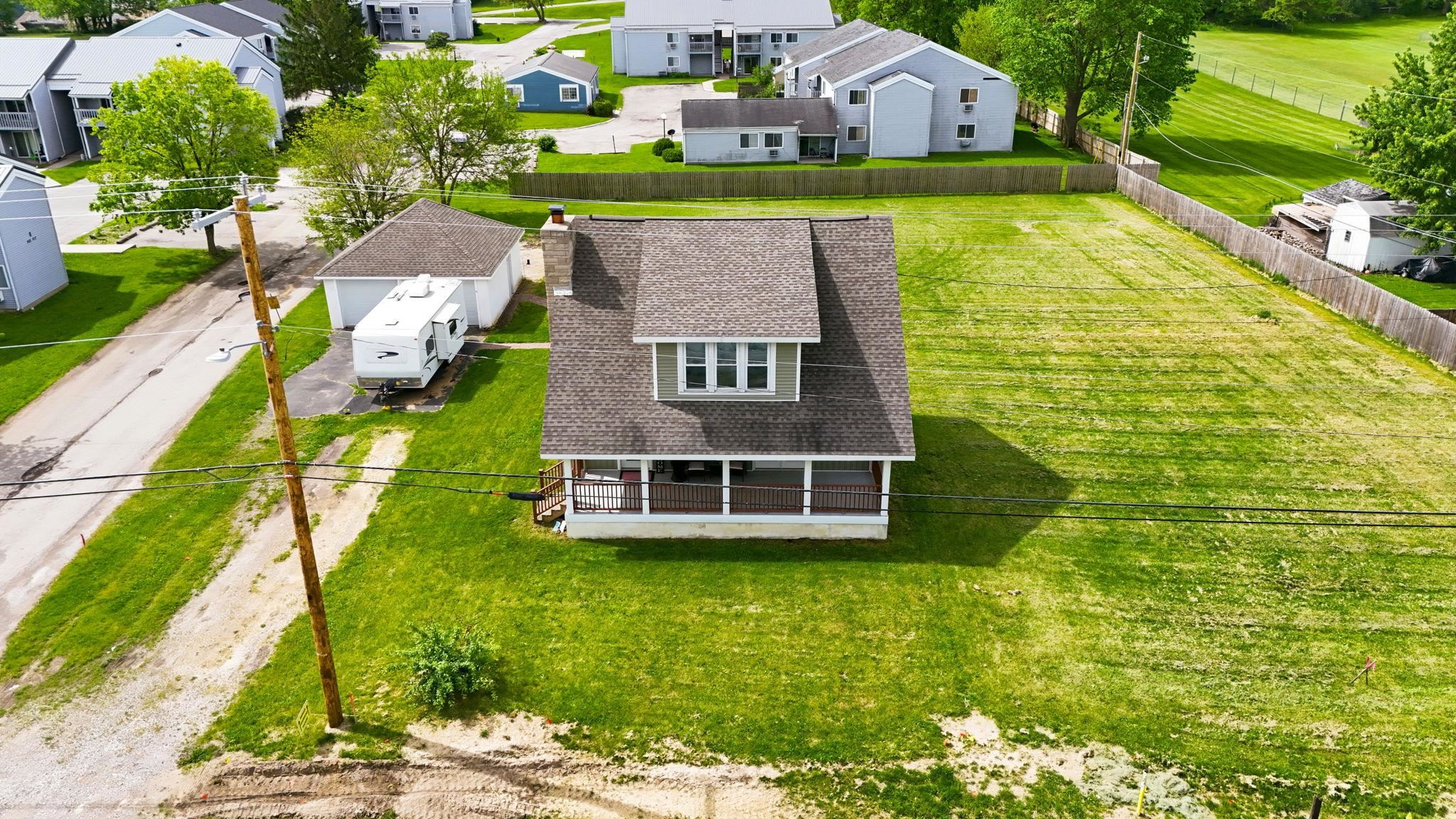 Traditional-style residence featuring a prominent front porch with white columns, a dormer window, and a gray shingle roof