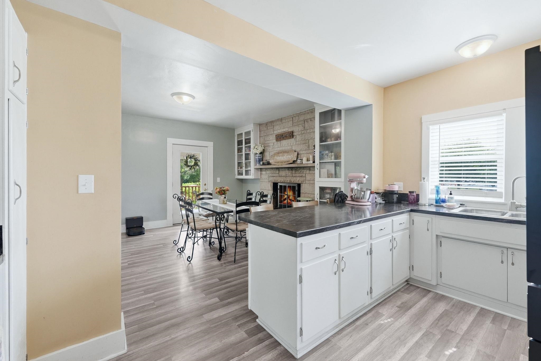 Kitchen featuring an island with dark countertops, white cabinetry with silver hardware, and wood-finish flooring