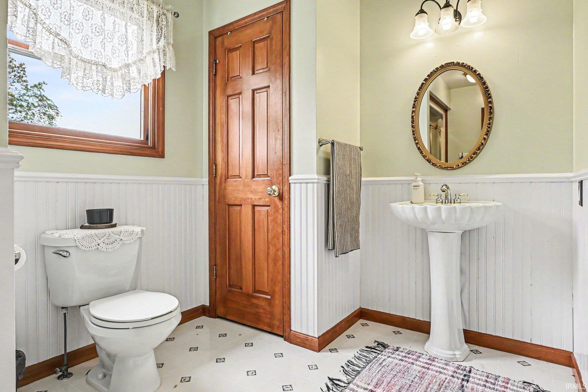 Pedestal sink with an ornate mirror and a three-light vanity fixture