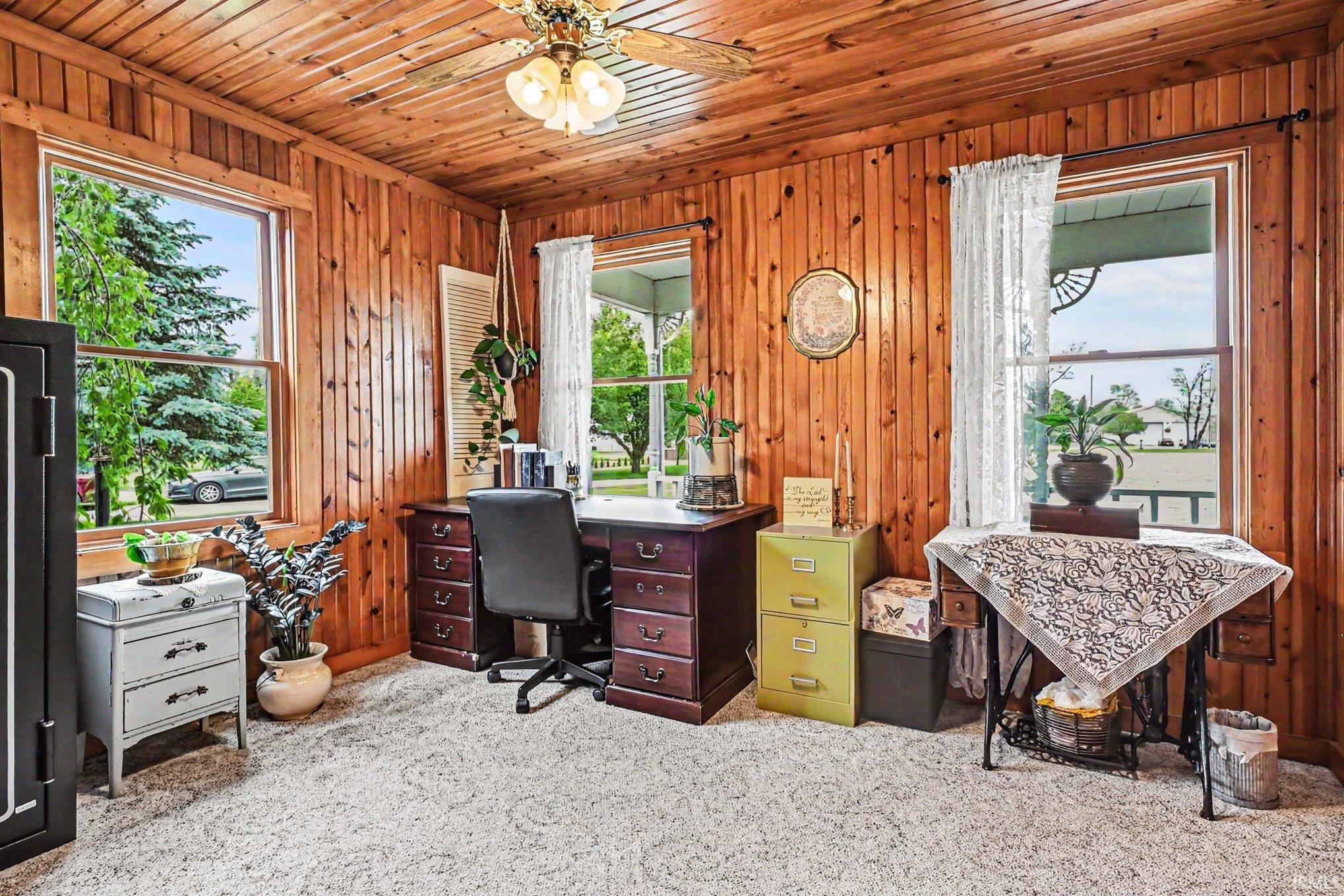 Room with wood-paneled walls and ceiling, featuring a ceiling fan with light fixture