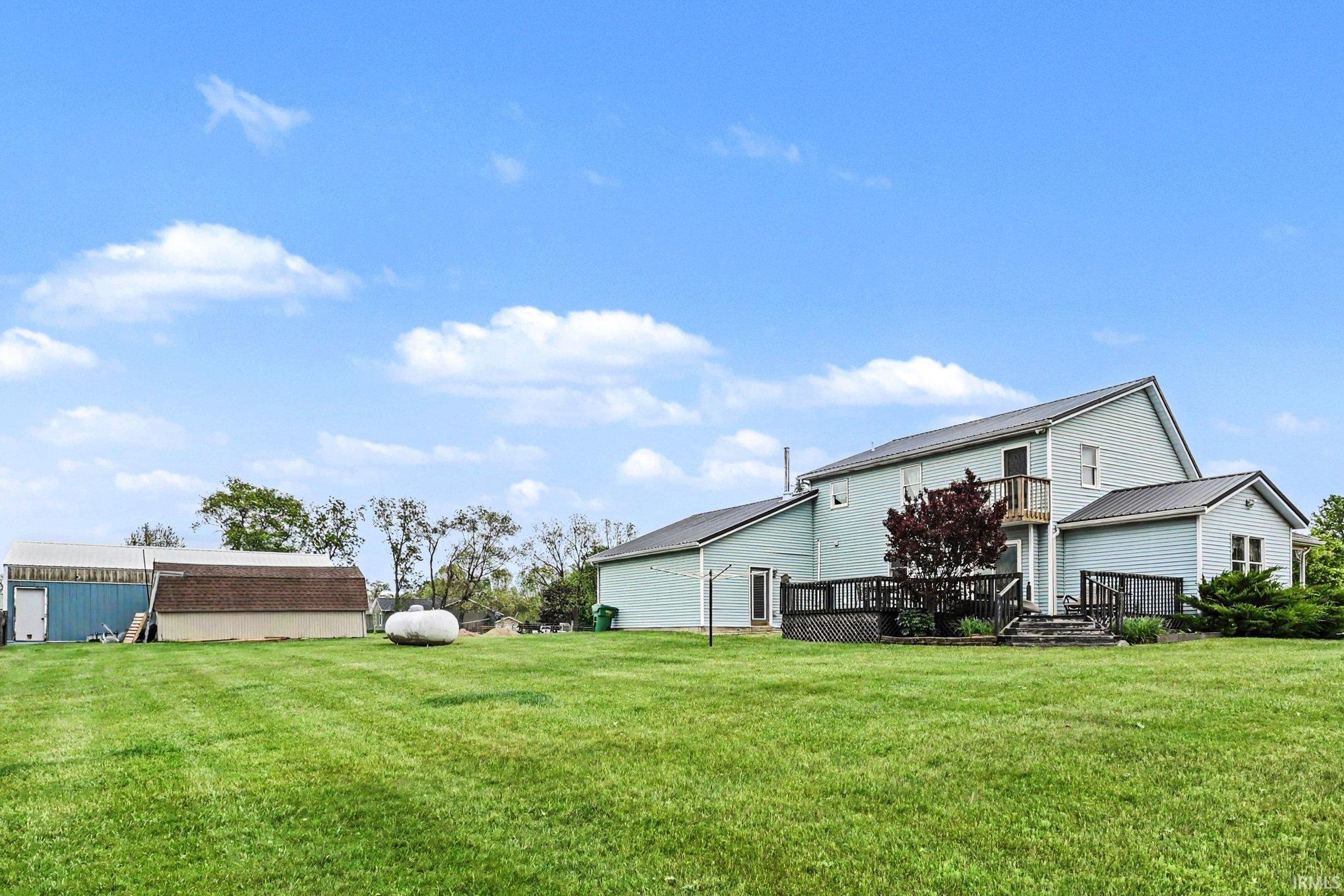 Expansive green lawn surrounding a light blue residence with a metal roof