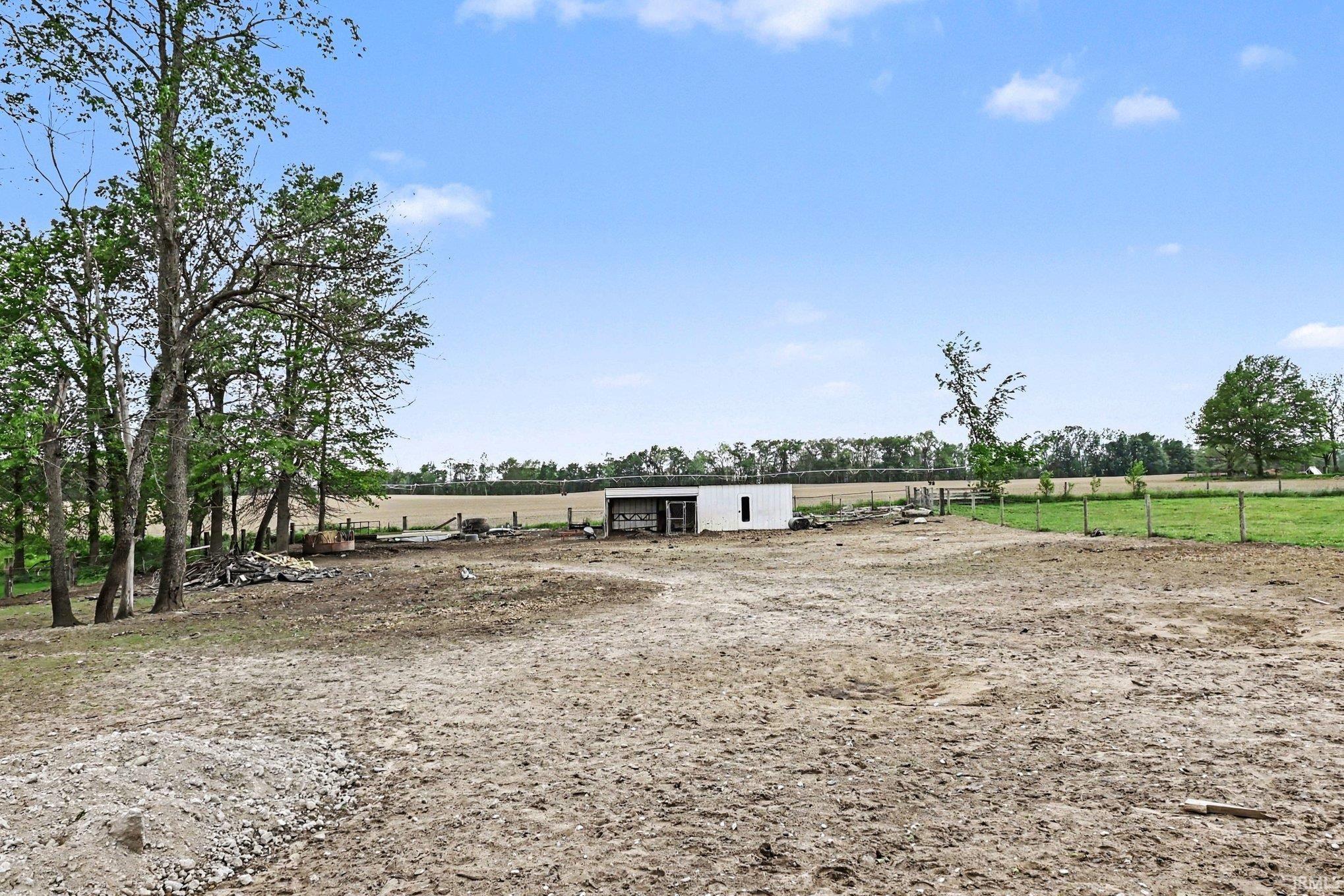 Expansive open plot featuring a small outbuilding, perimeter fencing, and mature trees