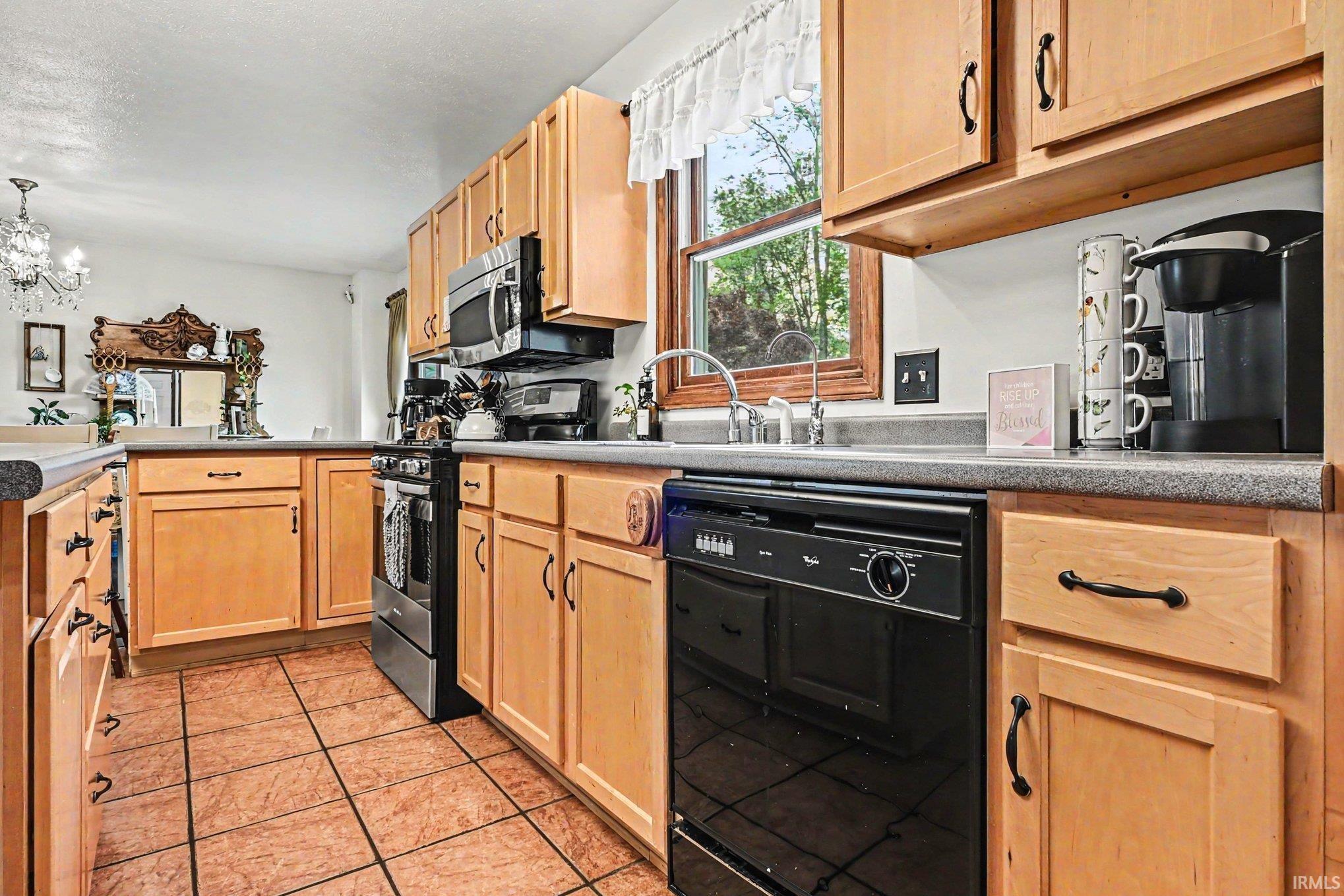 Kitchen featuring light wood cabinetry, stone-look countertops, stainless steel appliances, and tiled flooring