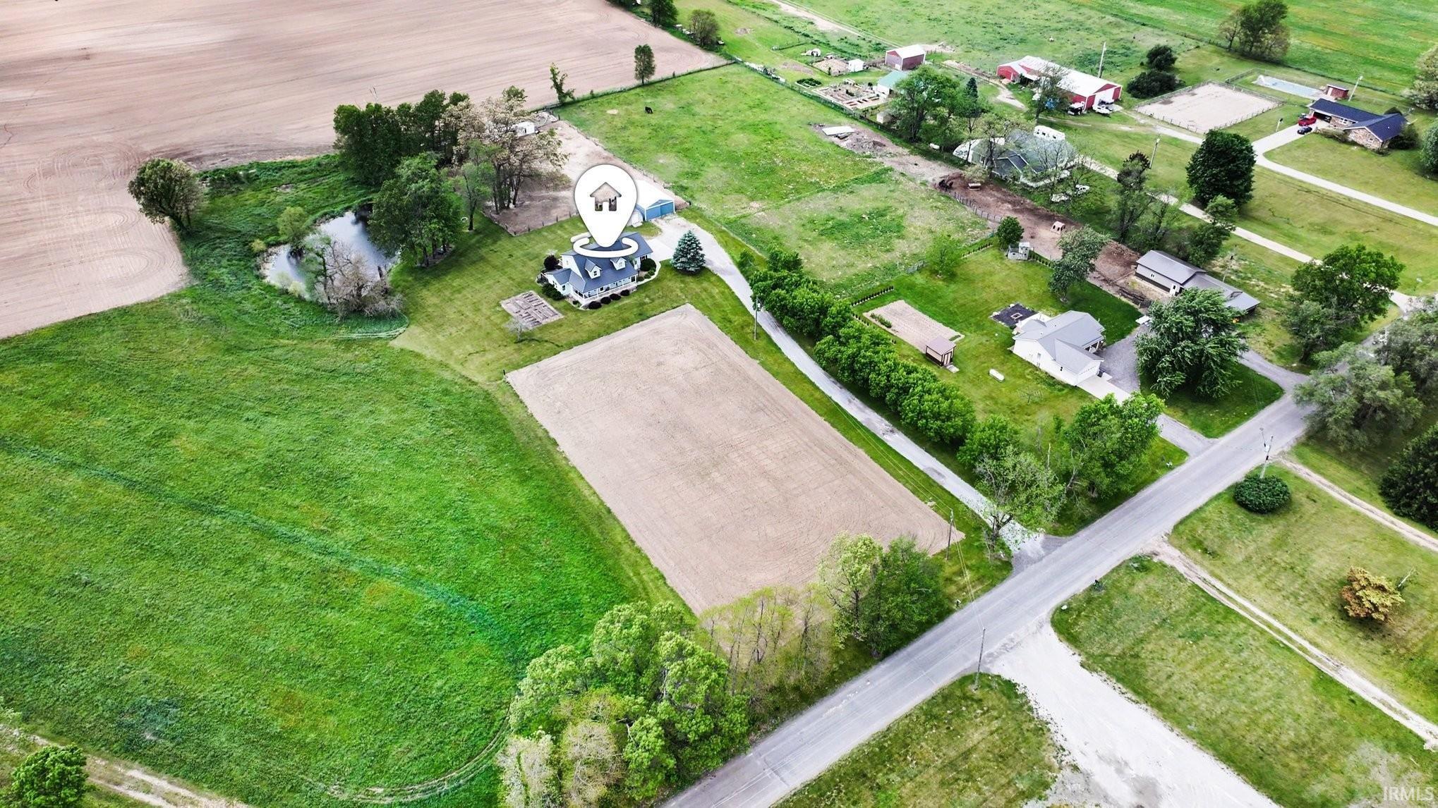 Expansive rural property featuring a main residence, cultivated fields, mature trees, and a private pond