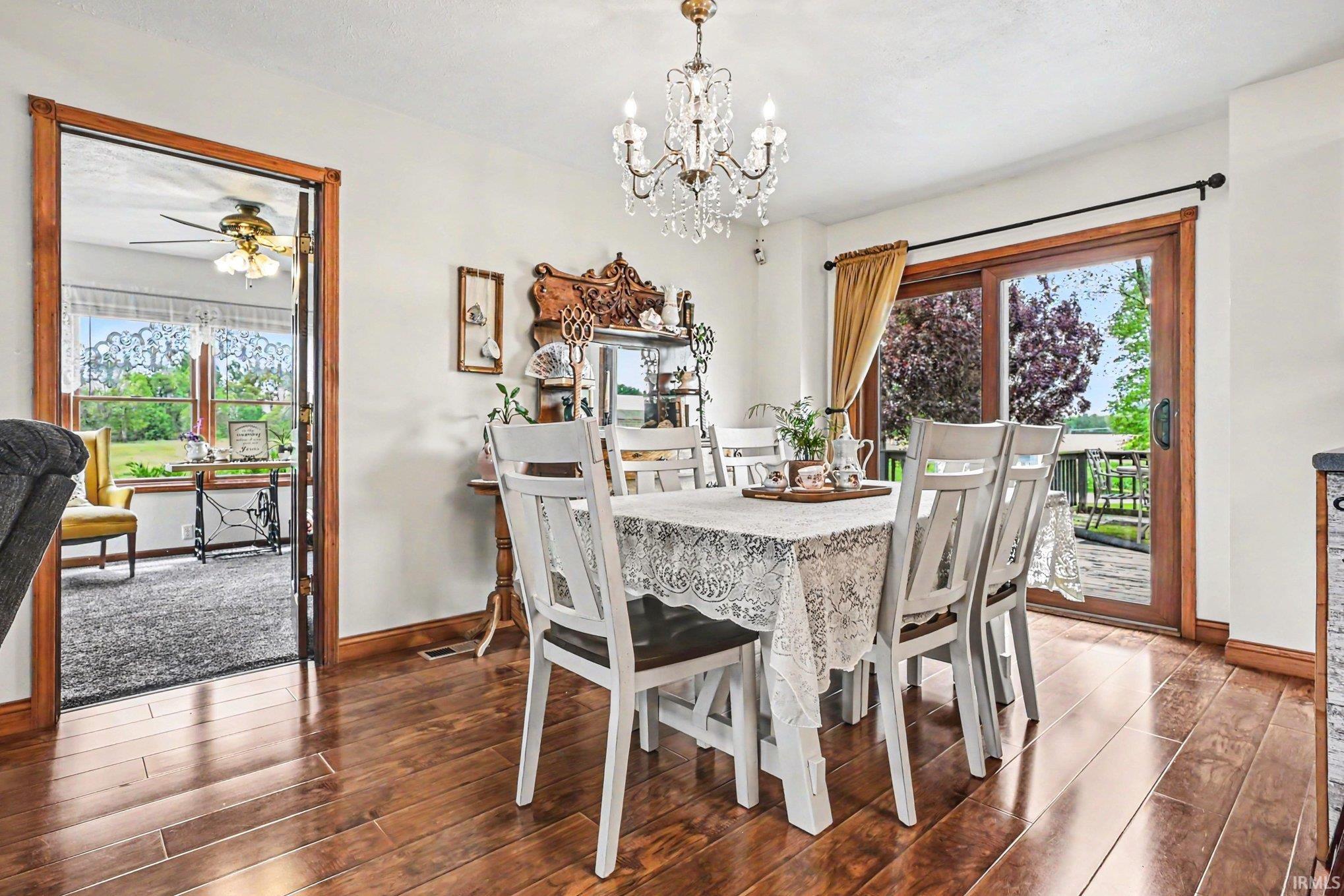 Dining area with wood-finish flooring, a crystal chandelier, and a sliding glass door providing access to an exterior deck