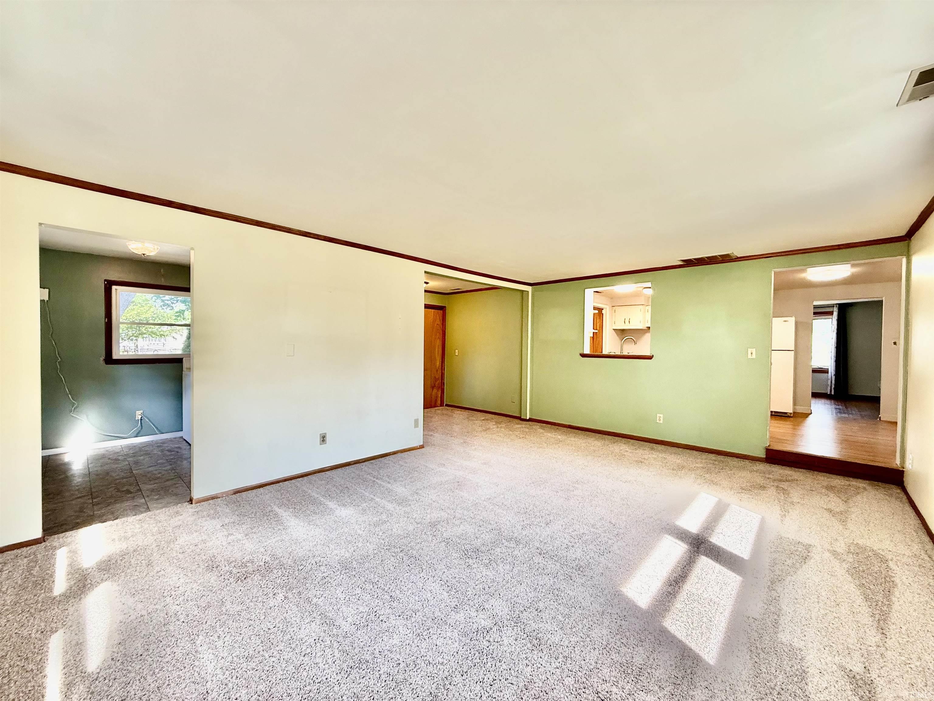 Expansive living area featuring carpet flooring and light green wall paint