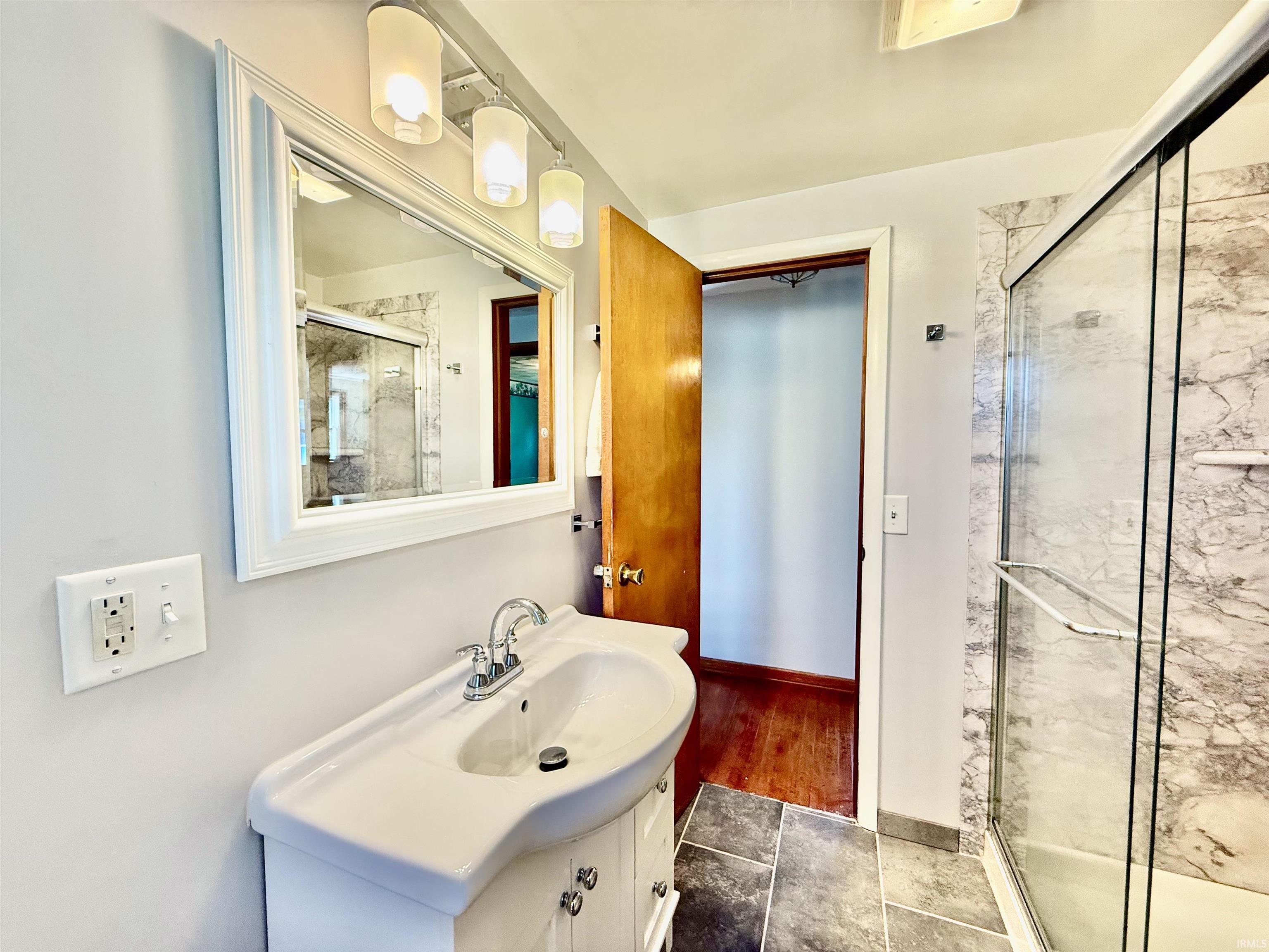 Bathroom featuring a white vanity with integrated sink, chrome faucet, and a framed mirror with track lighting