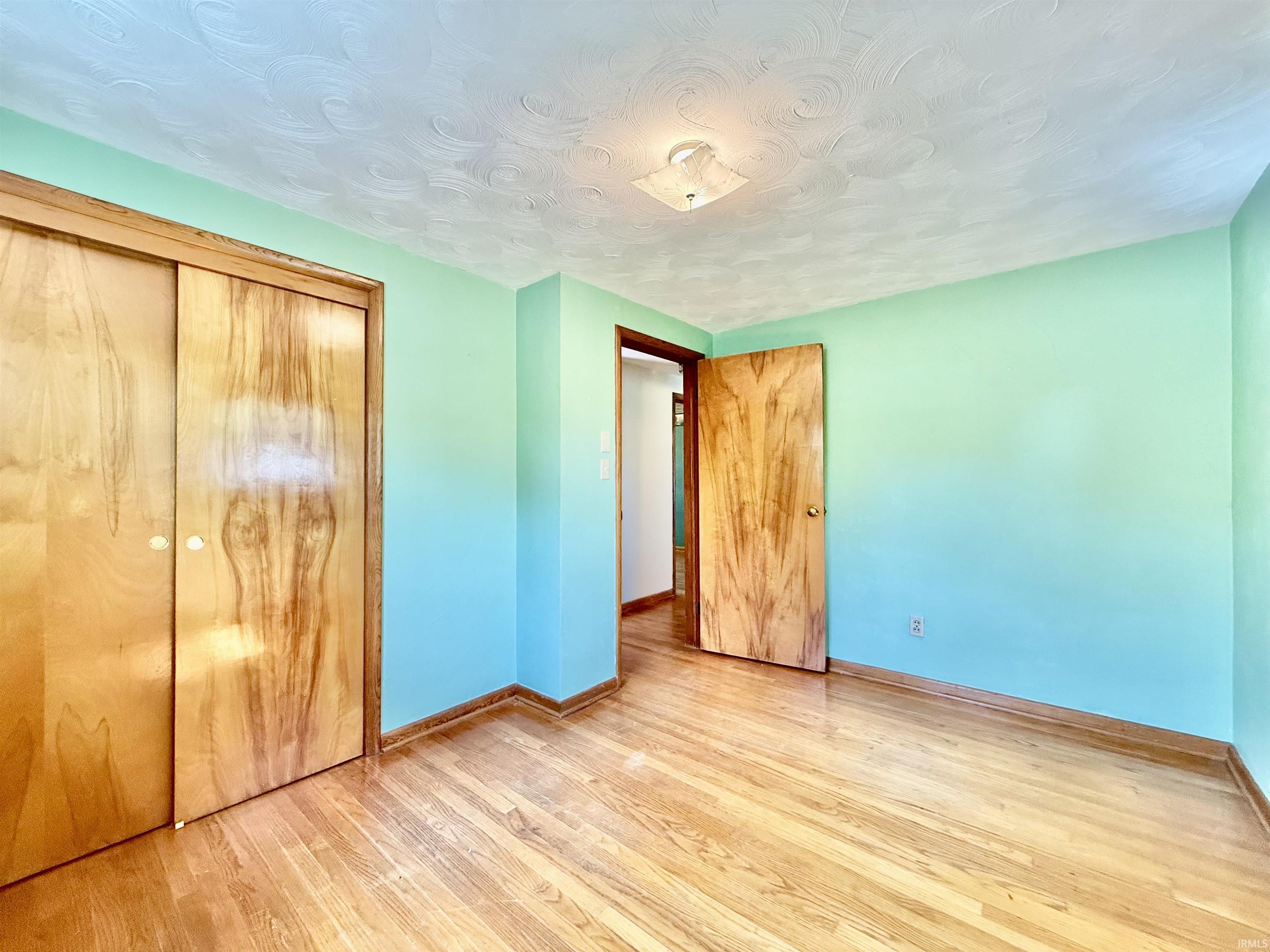 Room featuring wood-finish flooring, light blue walls, and a textured ceiling