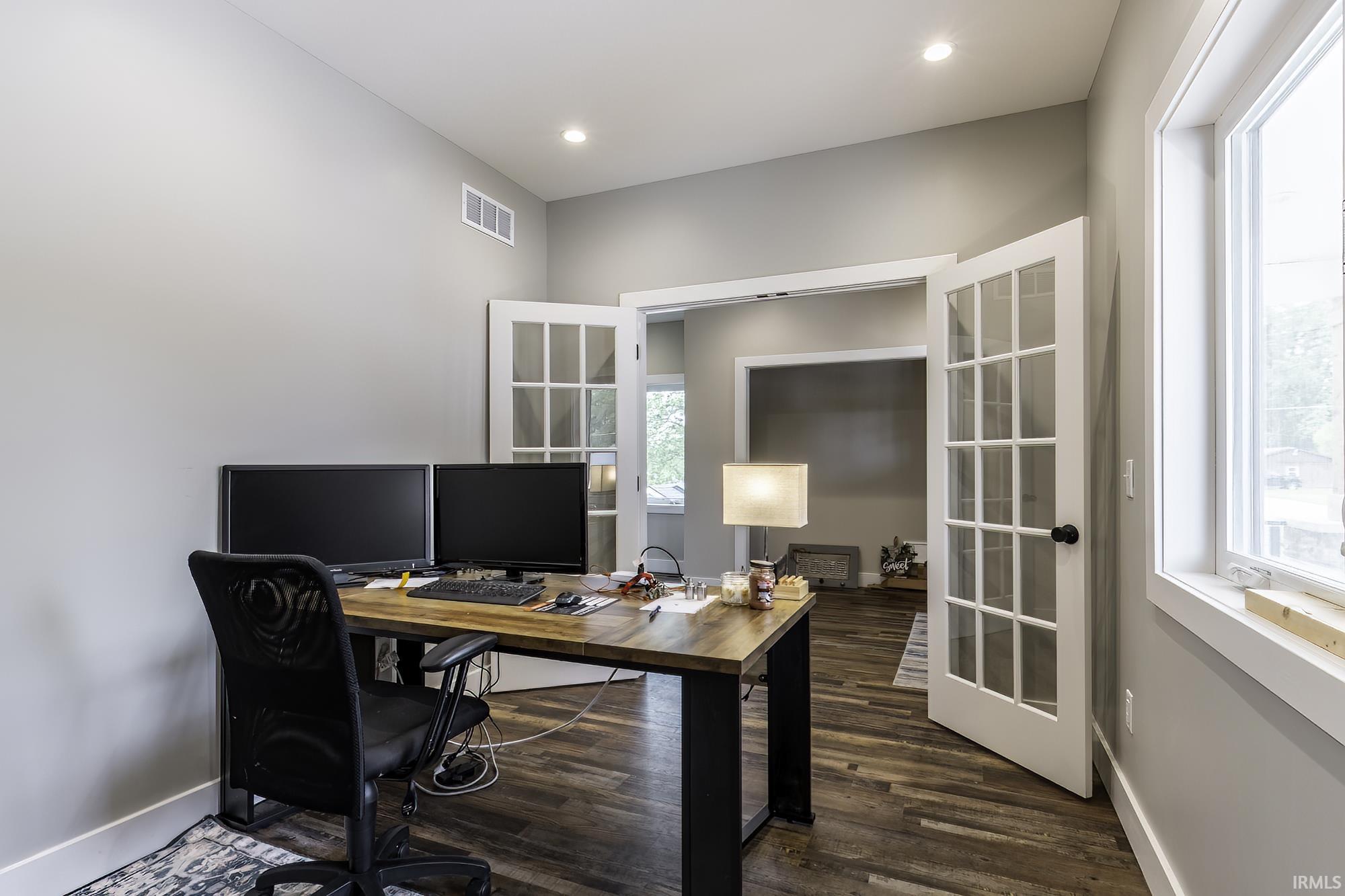 Room featuring wood-finish flooring, recessed lighting, and a window with white trim