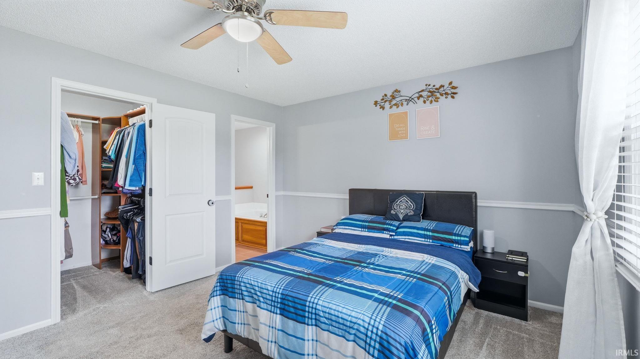 Bedroom featuring light gray wall paint, white chair rail molding, and gray carpet flooring