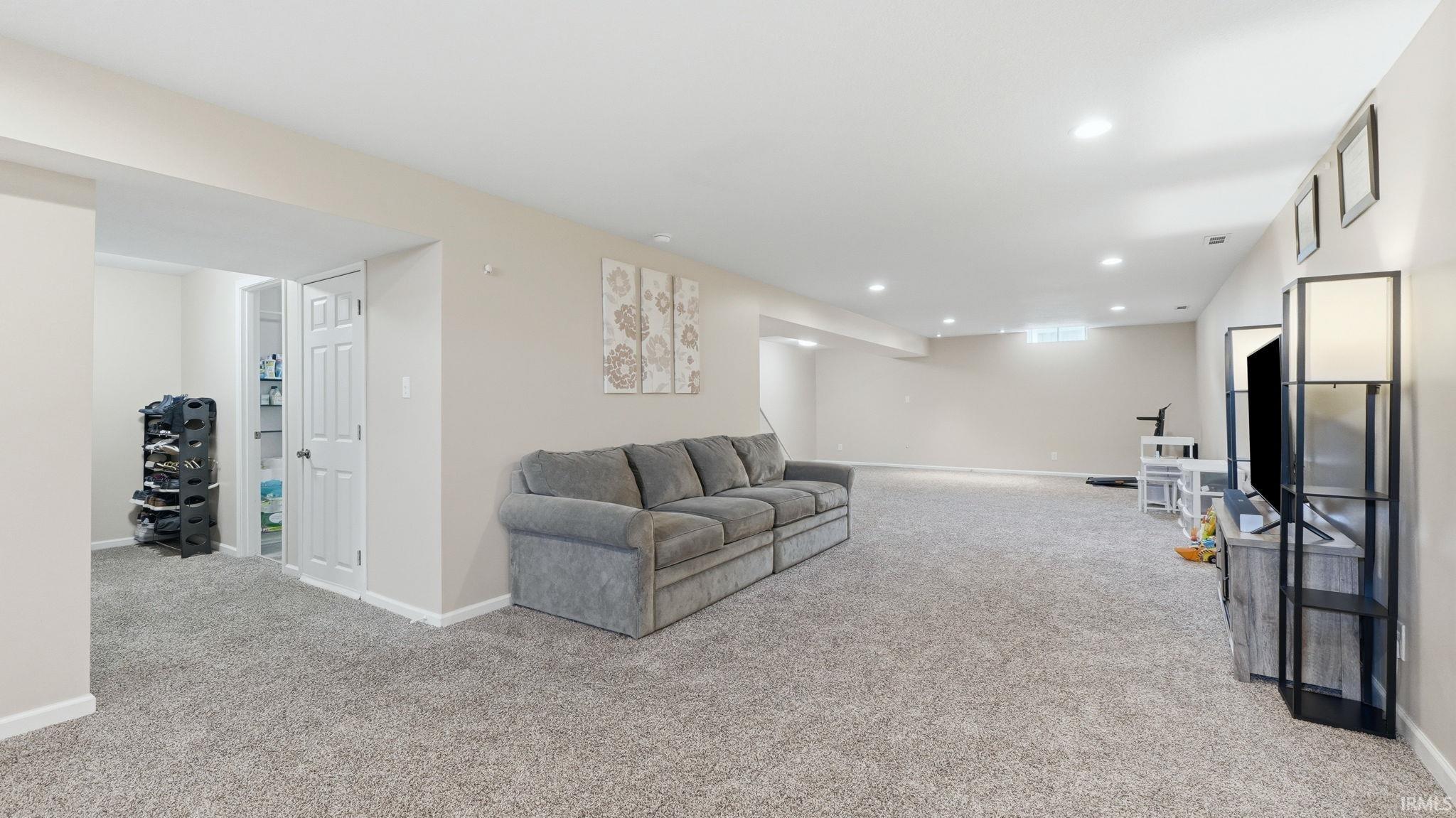 Spacious room featuring neutral carpeting, recessed lighting, a white painted door, and a horizontal window