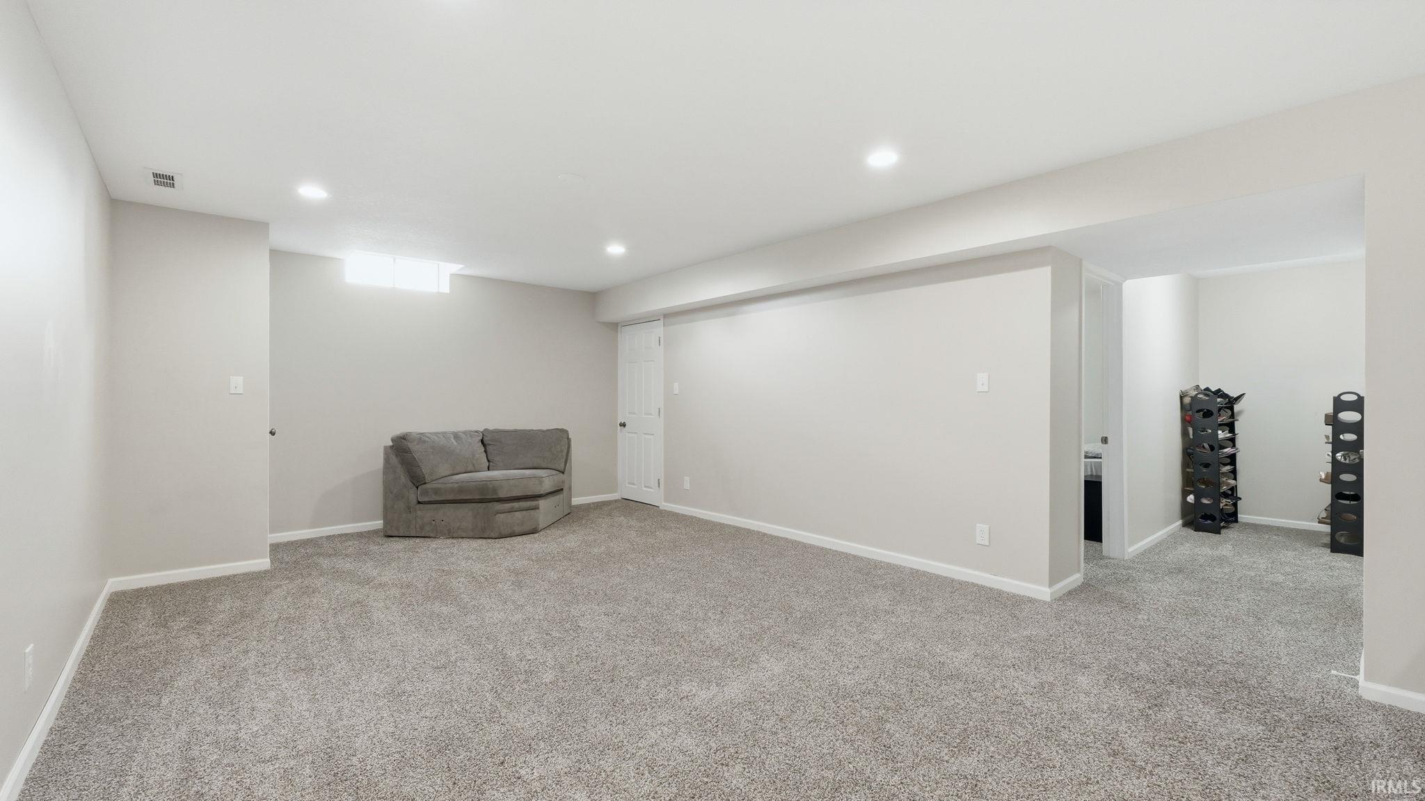 Spacious finished room featuring light gray carpeting, recessed lighting, and neutral wall paint