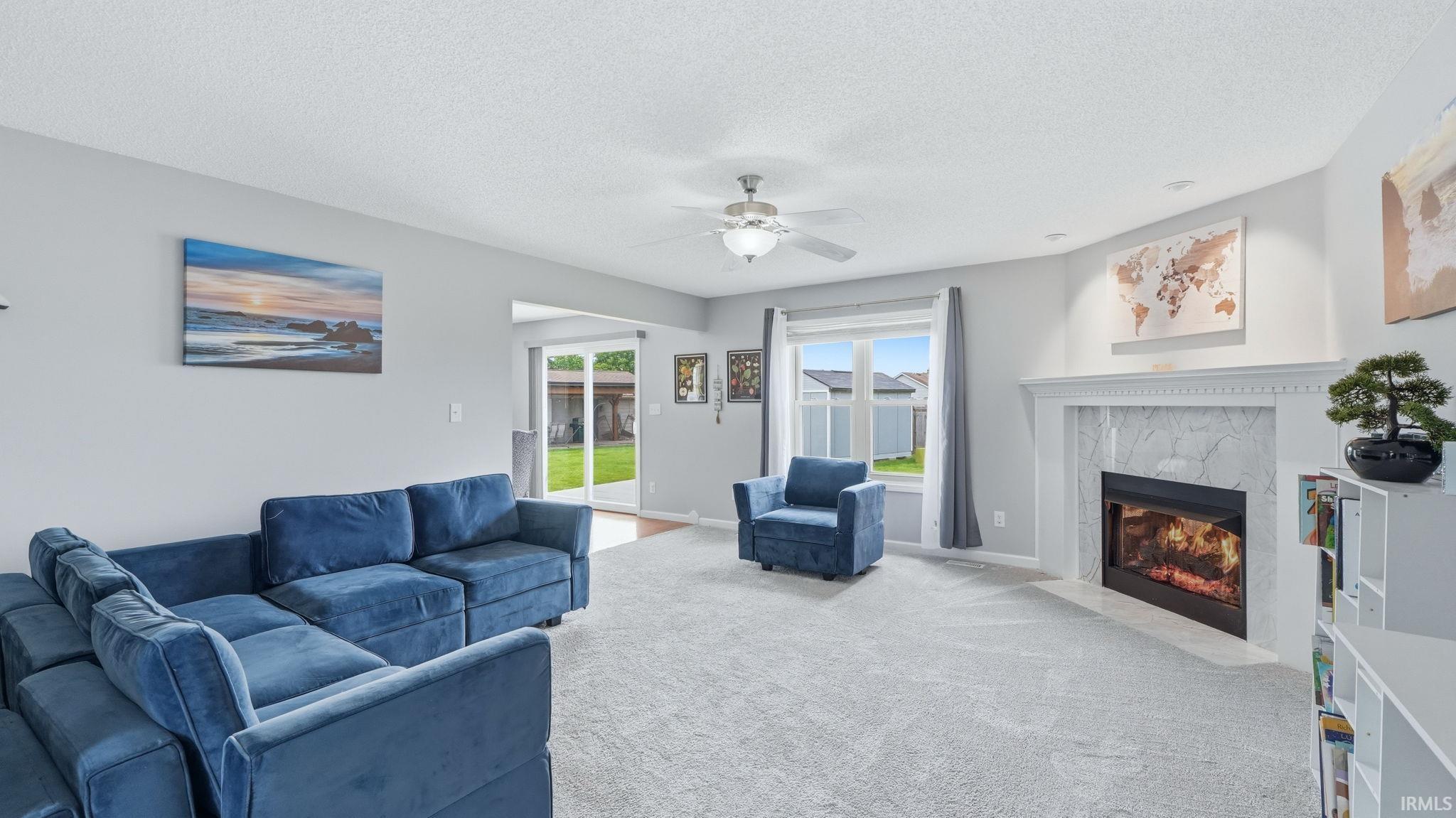 Living area with a fireplace featuring a white mantel and a light-toned stone surround