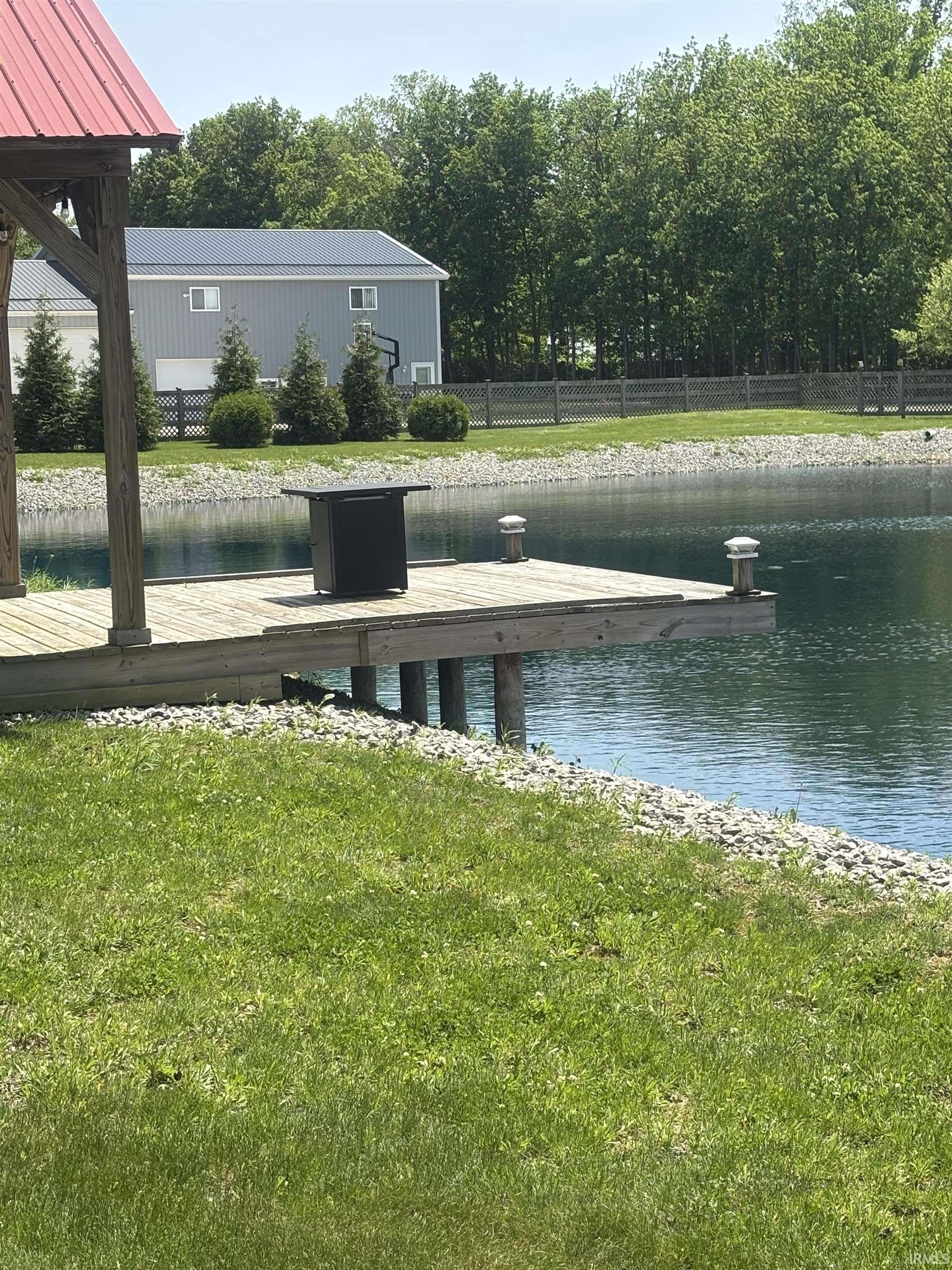 Private pond with a built-in dock, surrounded by lush green lawn and decorative gravel