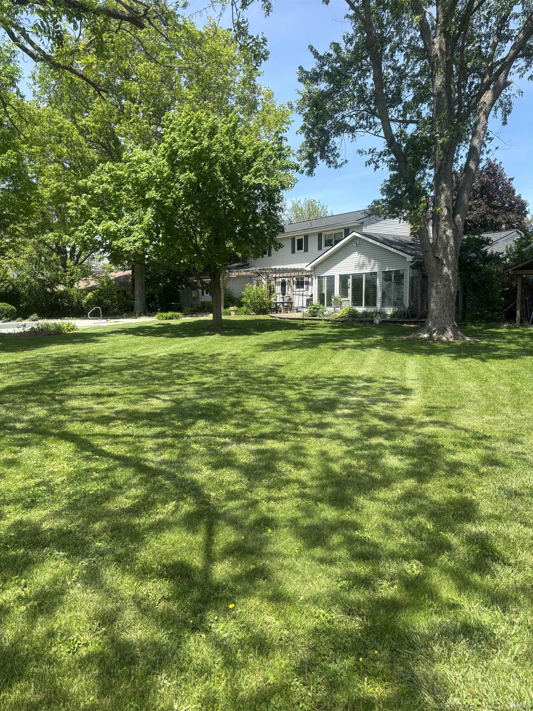 Expansive green lawn with mature trees providing shade