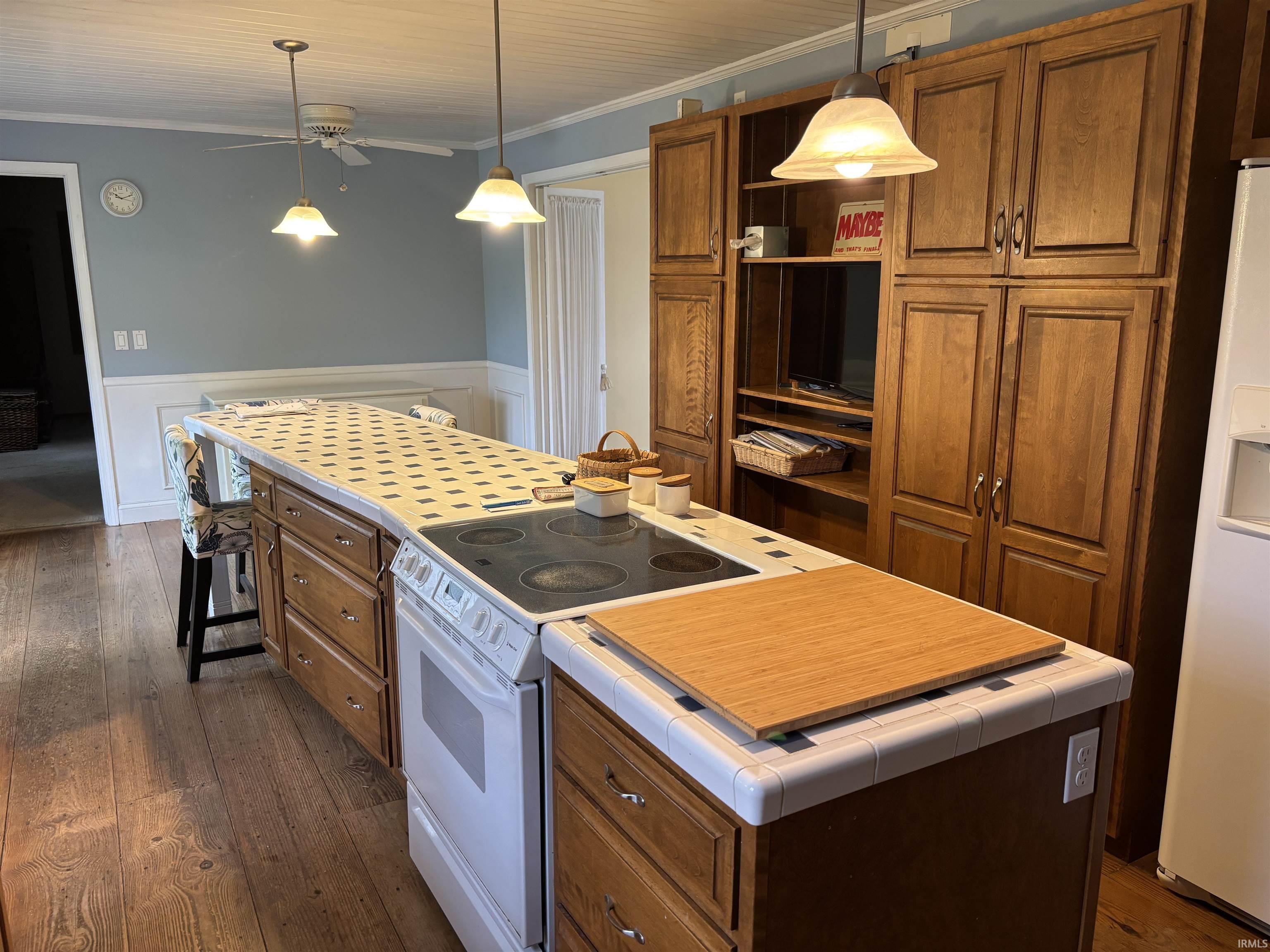 Kitchen island featuring a built-in electric range, tiled countertop, and ample storage cabinetry