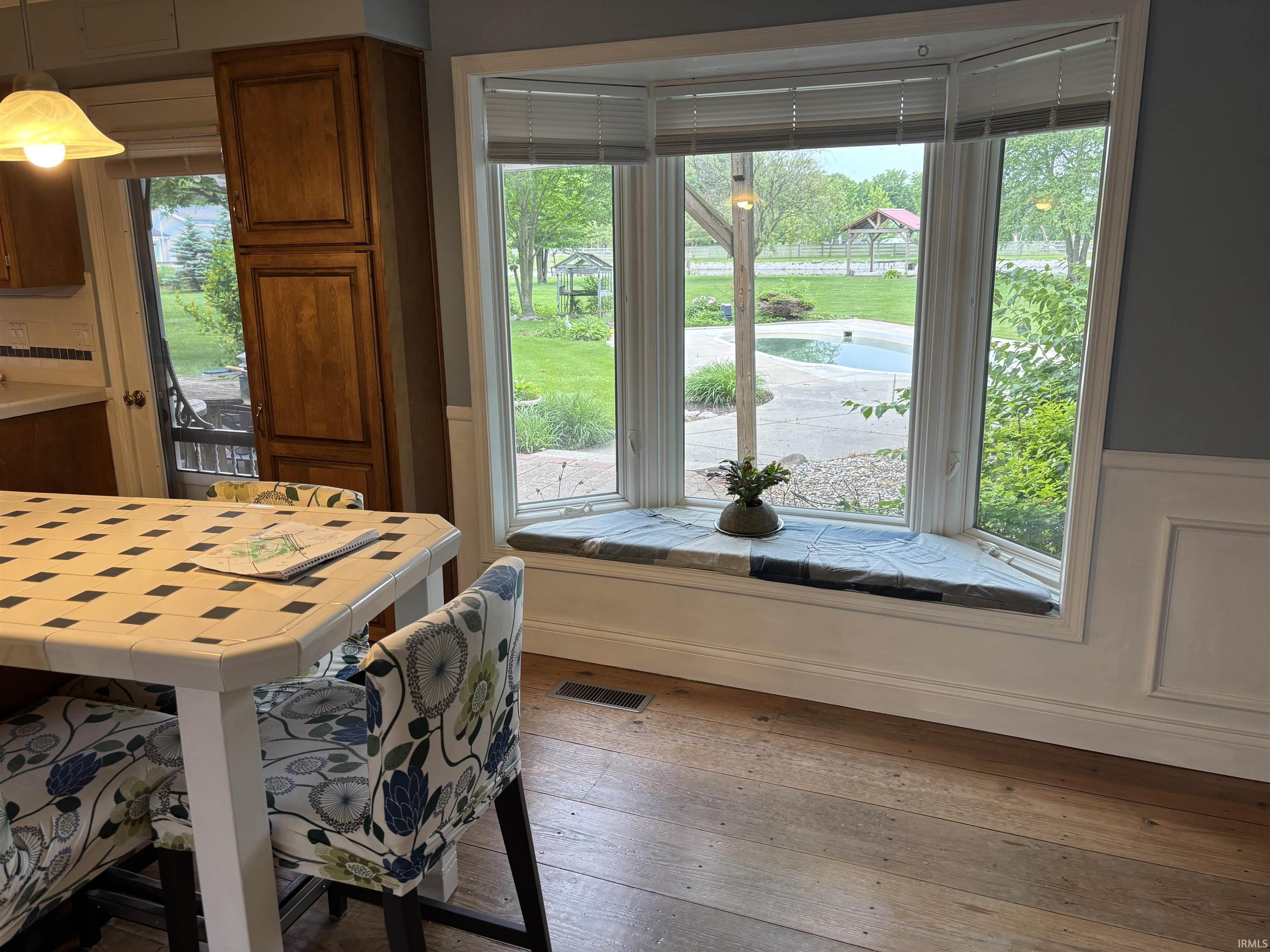 Expansive bay window featuring an integrated window seat overlooking a backyard with an in-ground pool