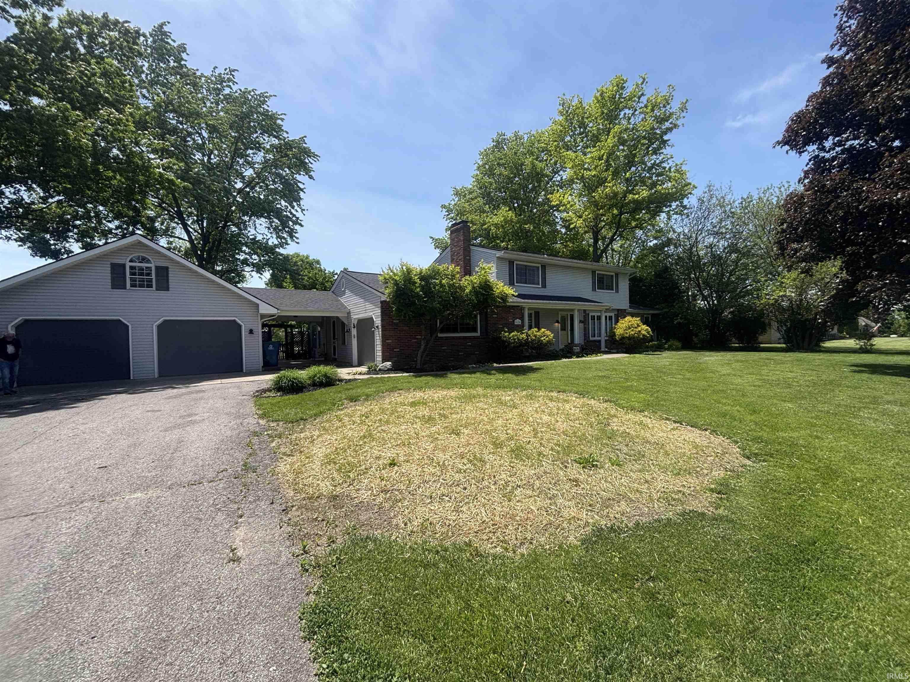 Two-story residence featuring a two-car garage with a second-story dormer window, a covered breezeway, and an additional single-car garage