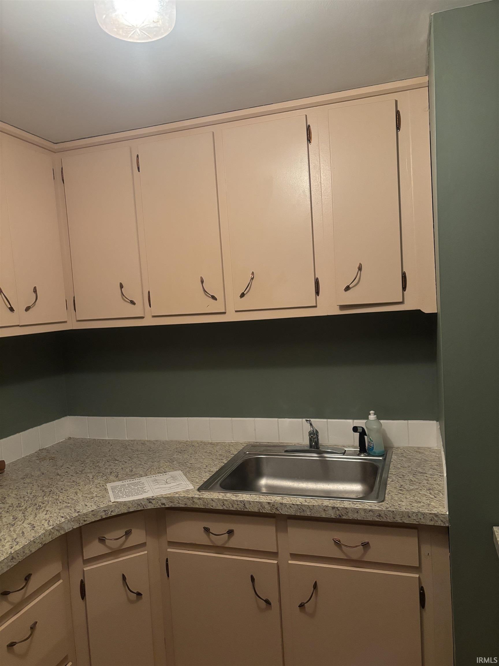 Galley kitchen featuring light-toned cabinetry, a stainless steel sink, and speckled countertops