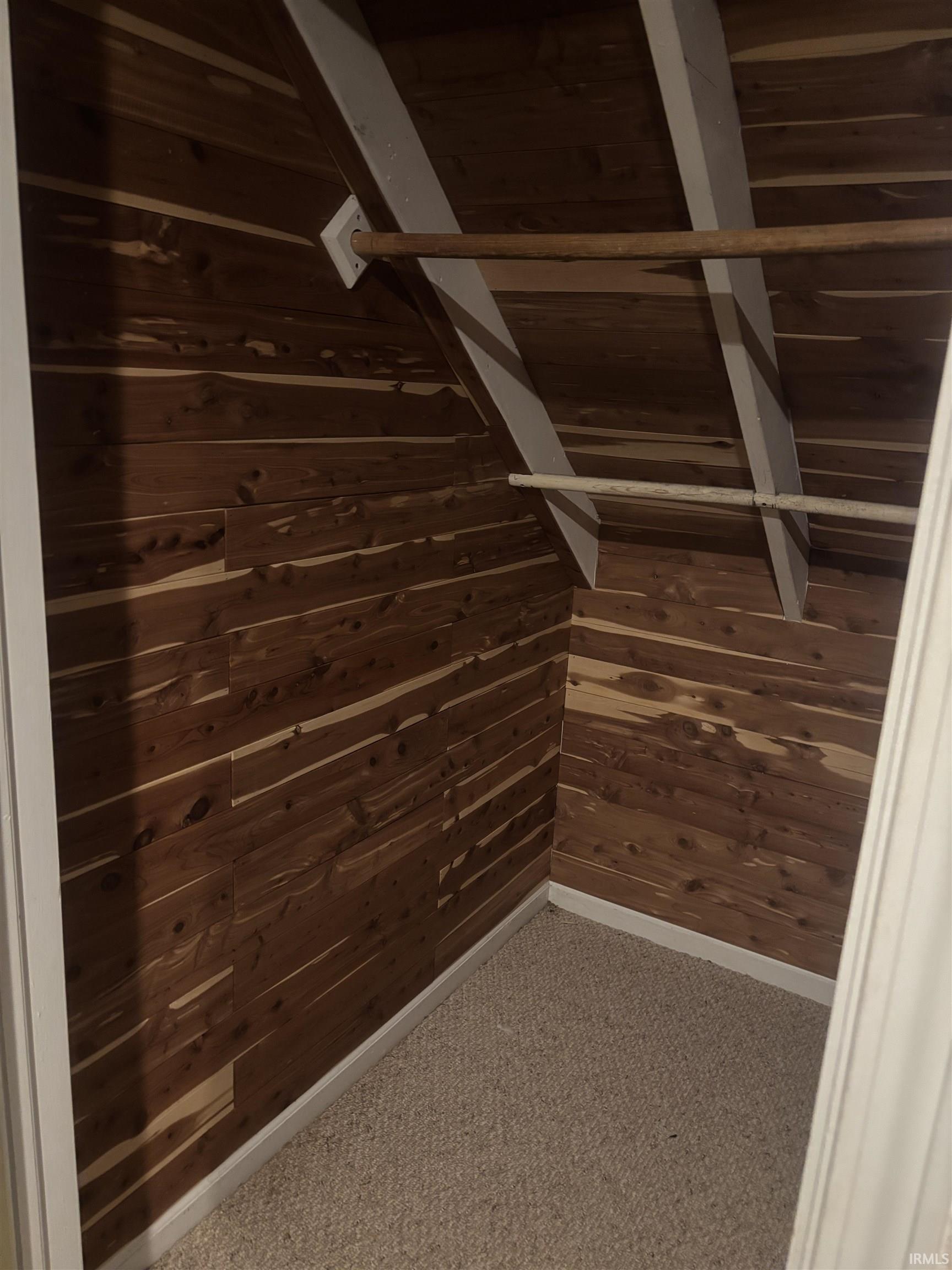 Cedar-lined closet featuring sloped ceiling with exposed white beams and two clothing rods