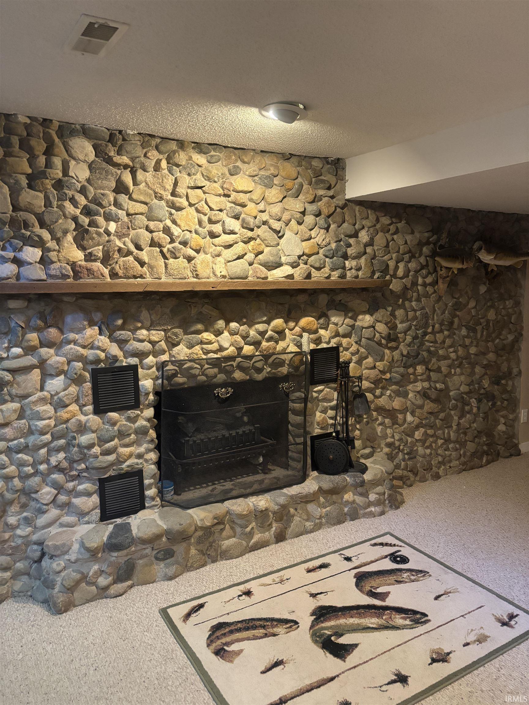 Stone-clad fireplace featuring a wood mantel