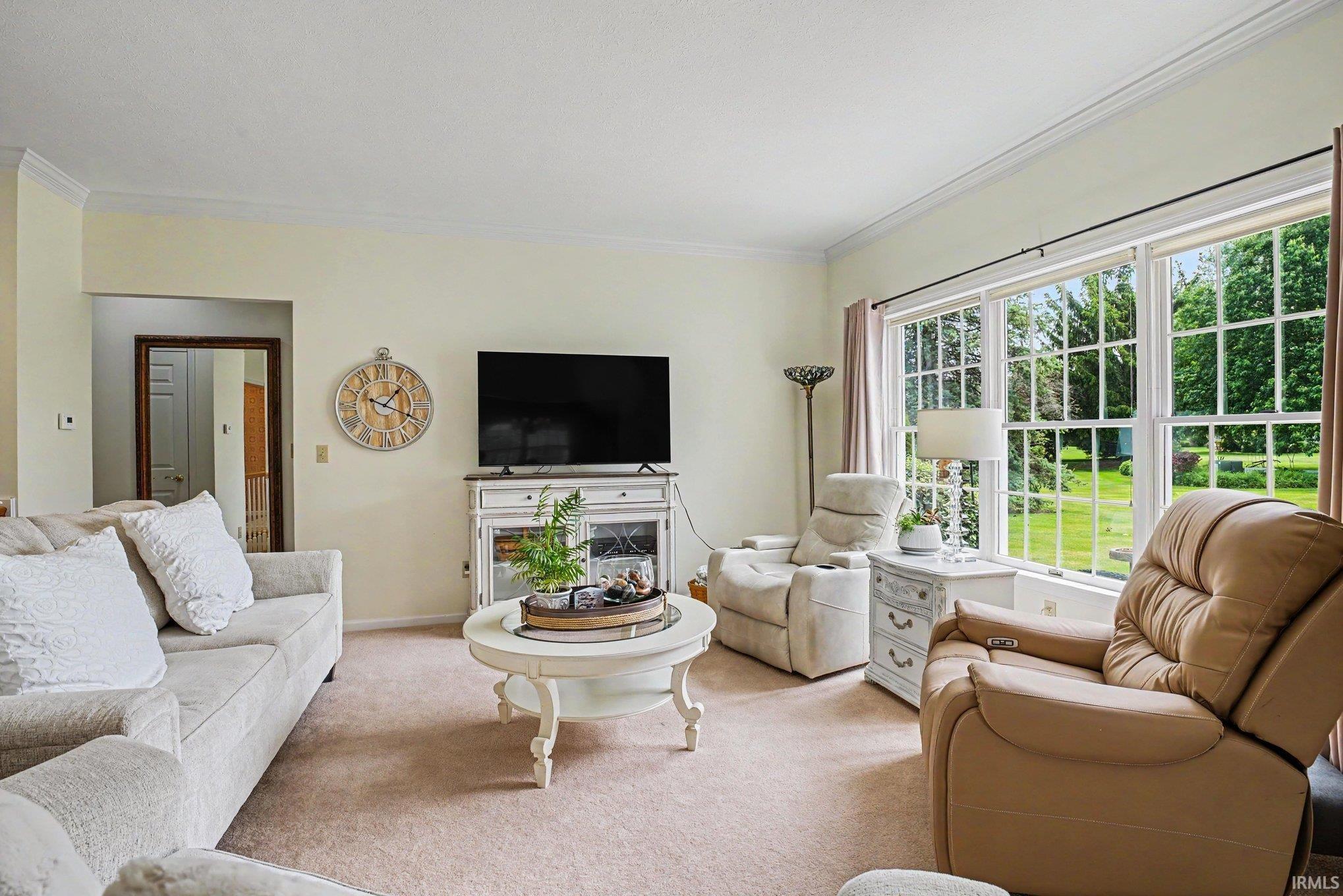 Living area featuring broad picture windows, crown molding, and neutral wall tones